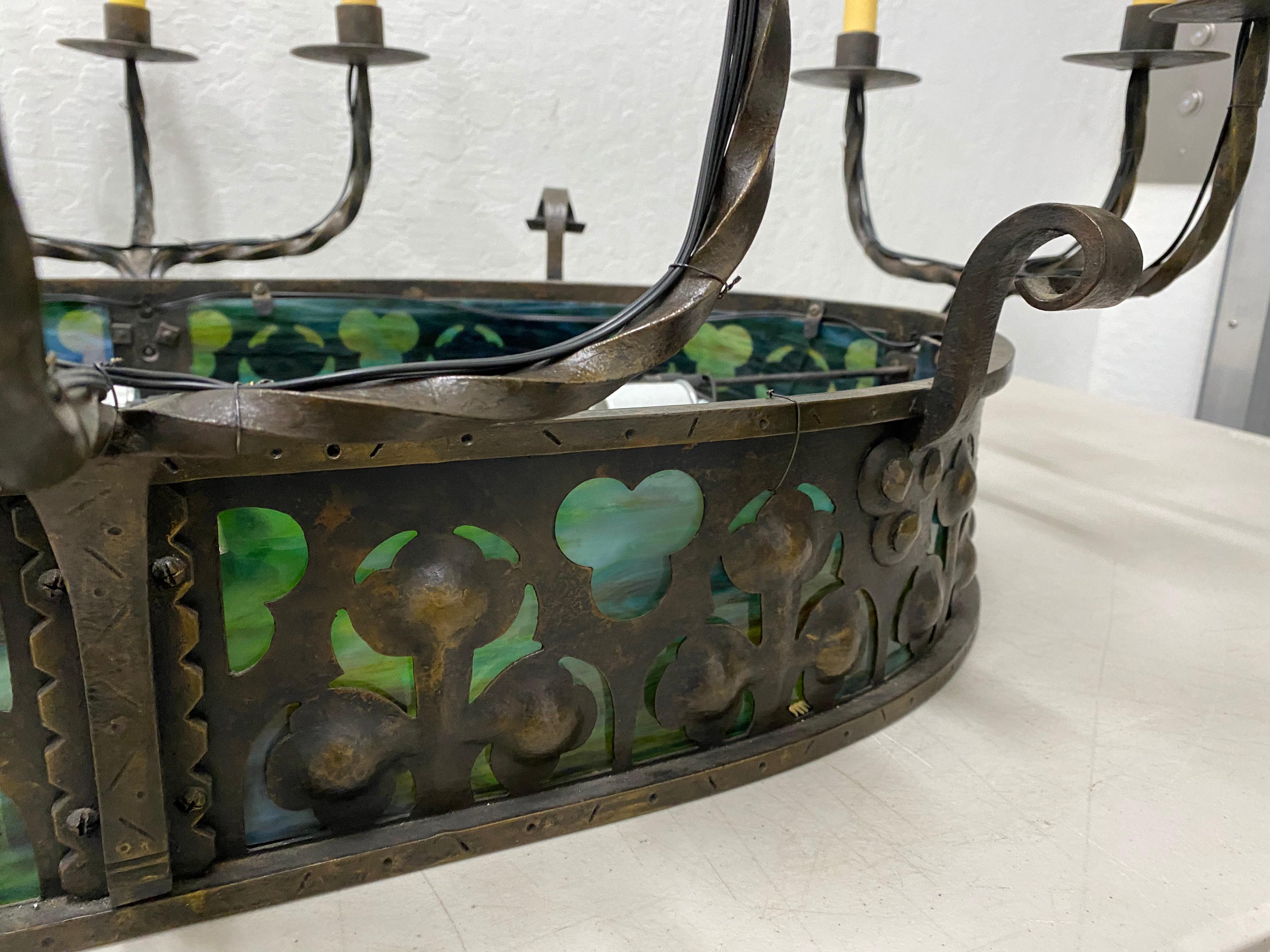 19th century French Gothic wrought iron and stained glass 12-light chandelier

Outstanding large scale chandelier.

Hand wrought iron chandelier with panels of stained glass surrounding the apron.

There is a small crack in one stained glass