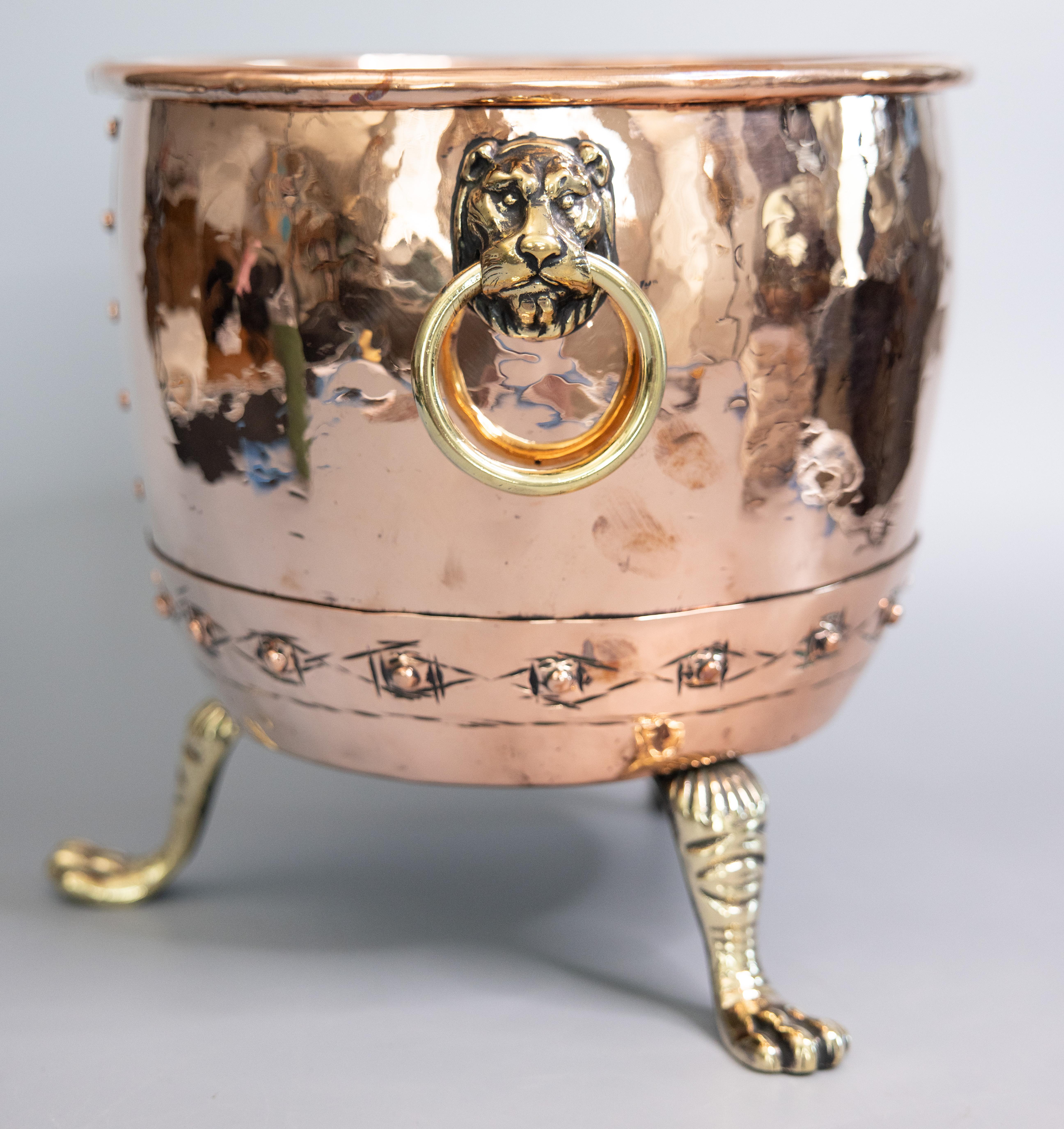 A superb large antique French hammered copper footed firewood holder / coal or log bucket / wine cooler / jardiniere, circa 1890. This fine hand crafted bucket is heavy and well made with a lovely copper patina, solid brass lion head handles, brass