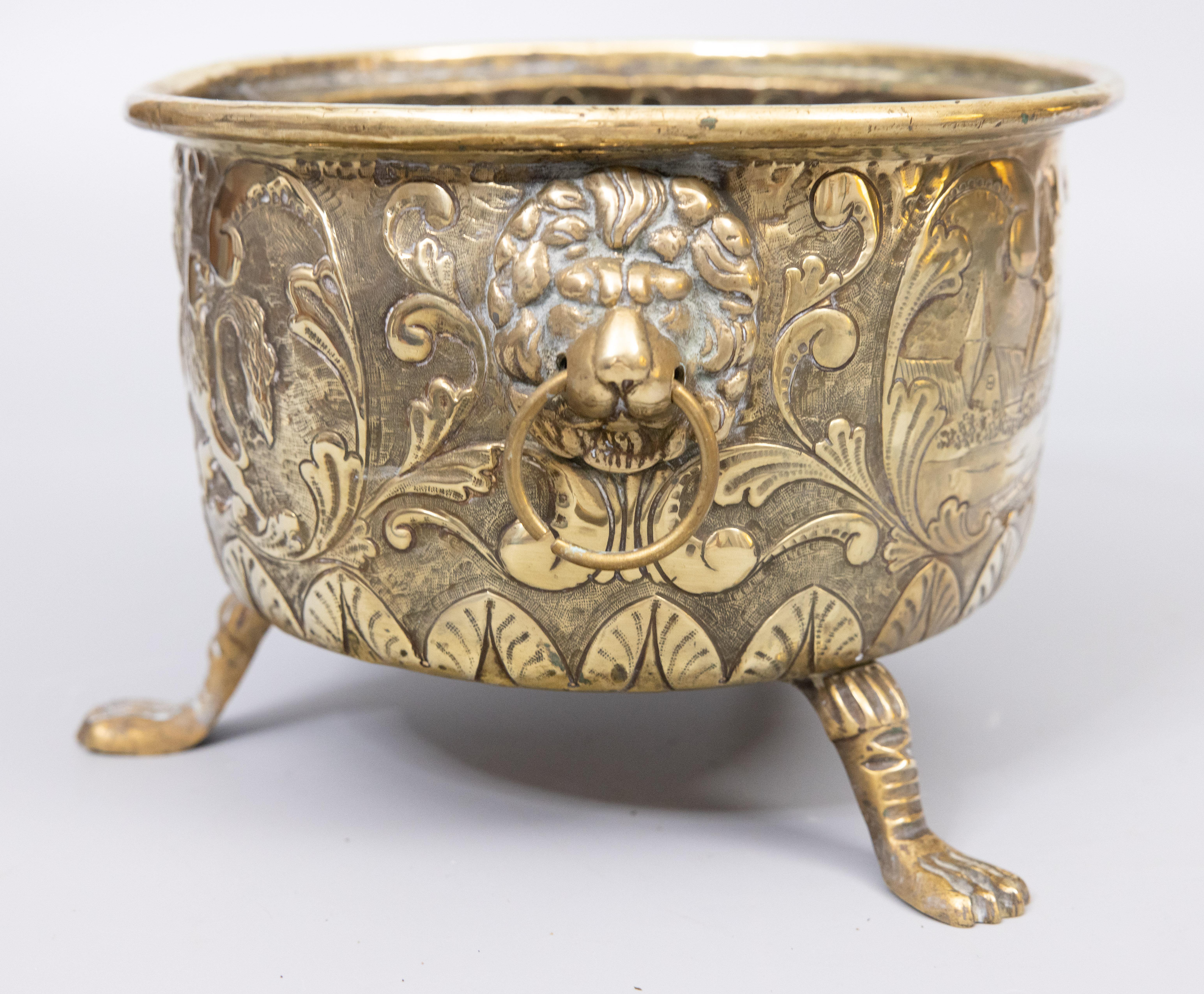 A superb antique 19th century French brass repoussé footed planter / jardiniere / cachepot, circa 1890. This fine hand crafted jardiniere is decorated with heraldic designs on one side and French country landscape scenes on the other side in a