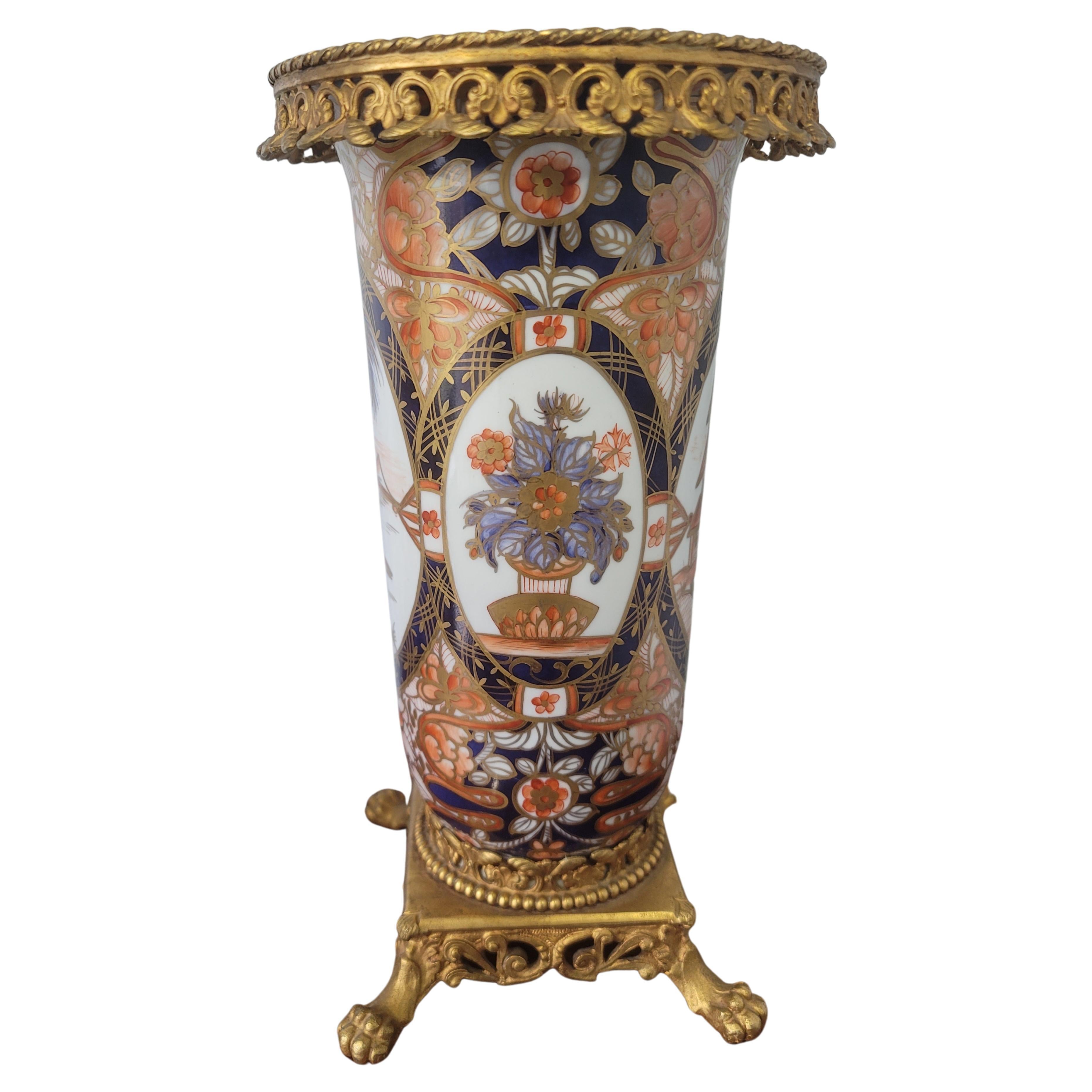 A rare, hand-painted  19th C. French Imari Porcelain Vase with Cast Brass Gallery and Base on Pawfeet, with fluted body of baluster form rising to an open mouth. The top is decorated with a dense and abundant cast brass gallery. The body is