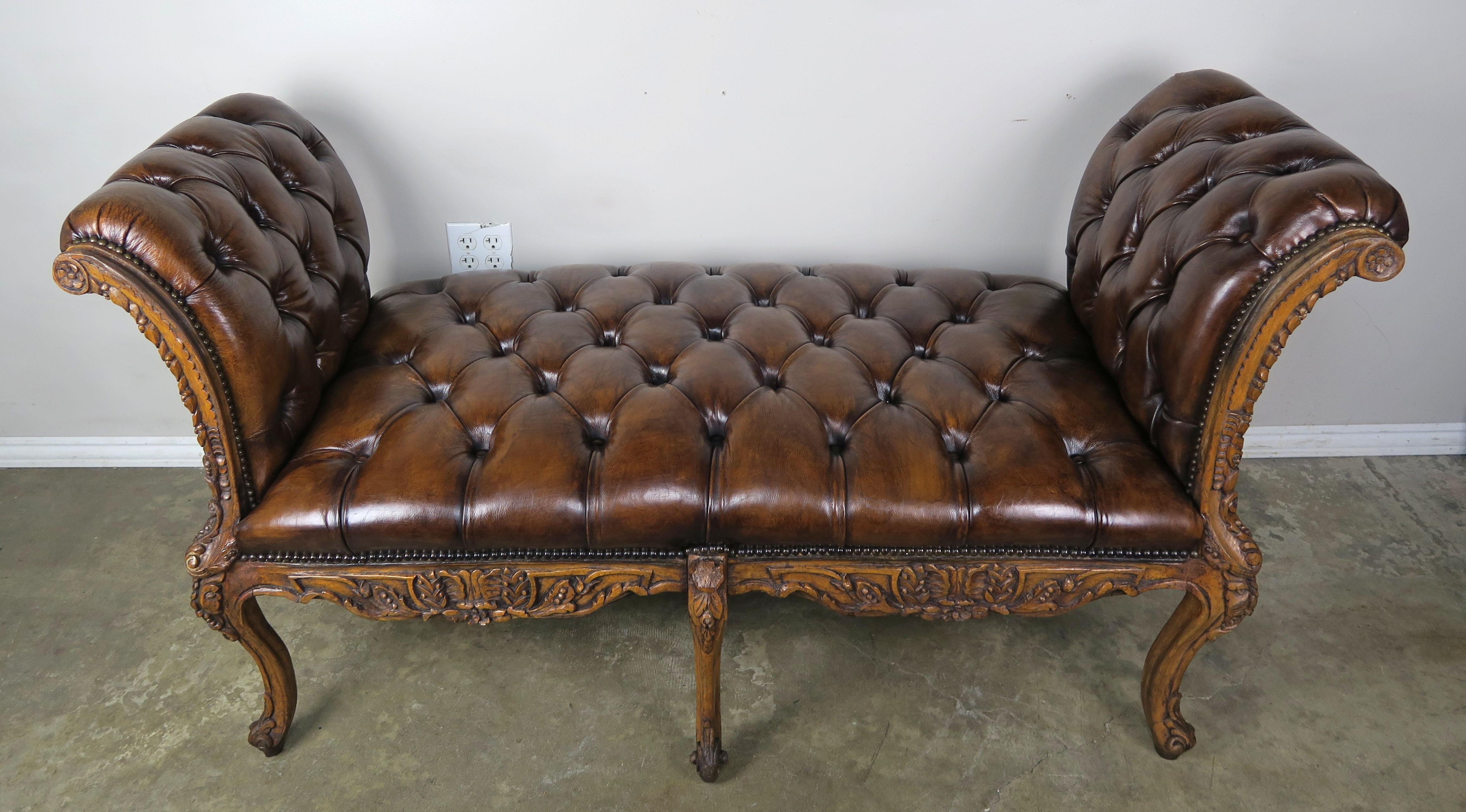 19th century French leather tufted bench that stands on six ornately carved cabriole legs that end in rams head feet. The bench is fabricated from walnut with parcel gilt detailing. The leather is beautifully distressed with no tears or cracks. The