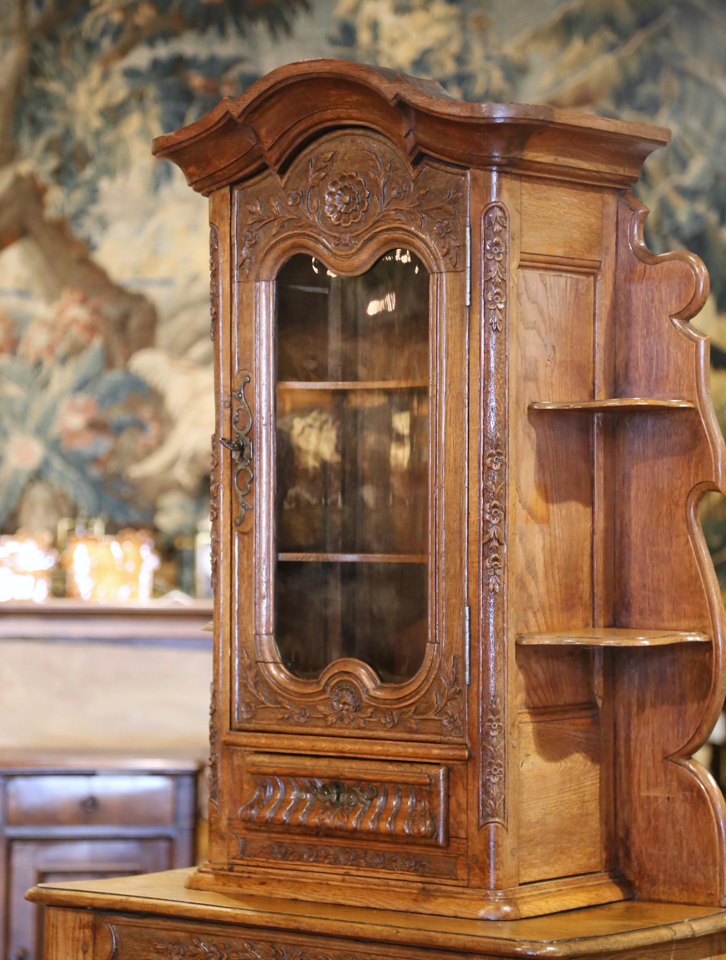Este encantador armario de dos piezas se fabricó en Normandía, Francia, hacia 1870, en estilo Luis XV, mezclando elegantes curvas con rusticidad regional. Fabricada en roble veteado, la parte inferior funciona como confitero, con una puerta de un