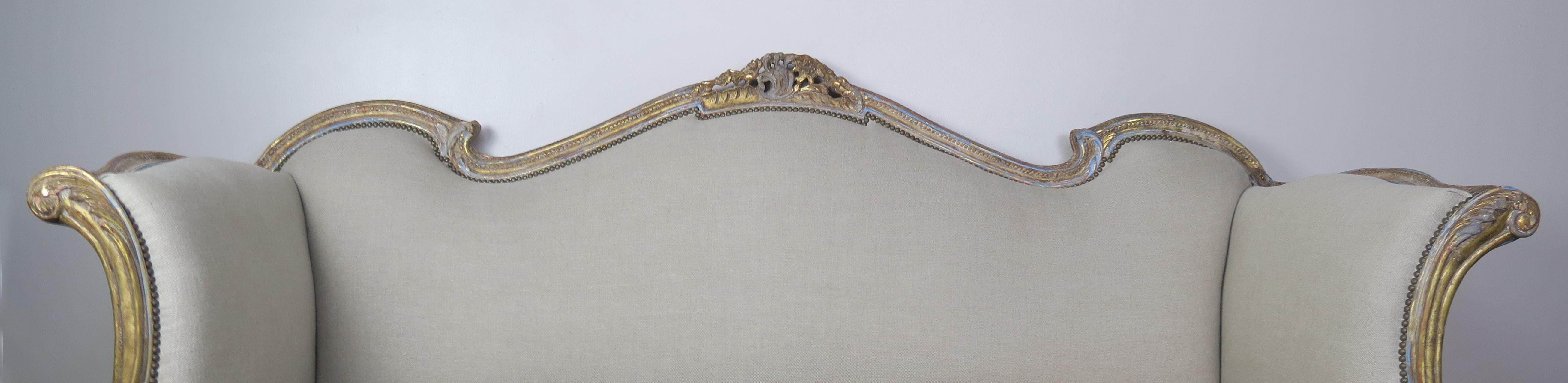 gemaltes und paketvergoldetes französisches Sofa im Stil von Louis XV aus dem 19. Das Sofa hat exquisite Linien und ist in einer französischen Blau- und Goldtönung mit 22-karätigen Blattgoldakzenten gehalten. Das Sofa ist mit naturfarbenem Leinen