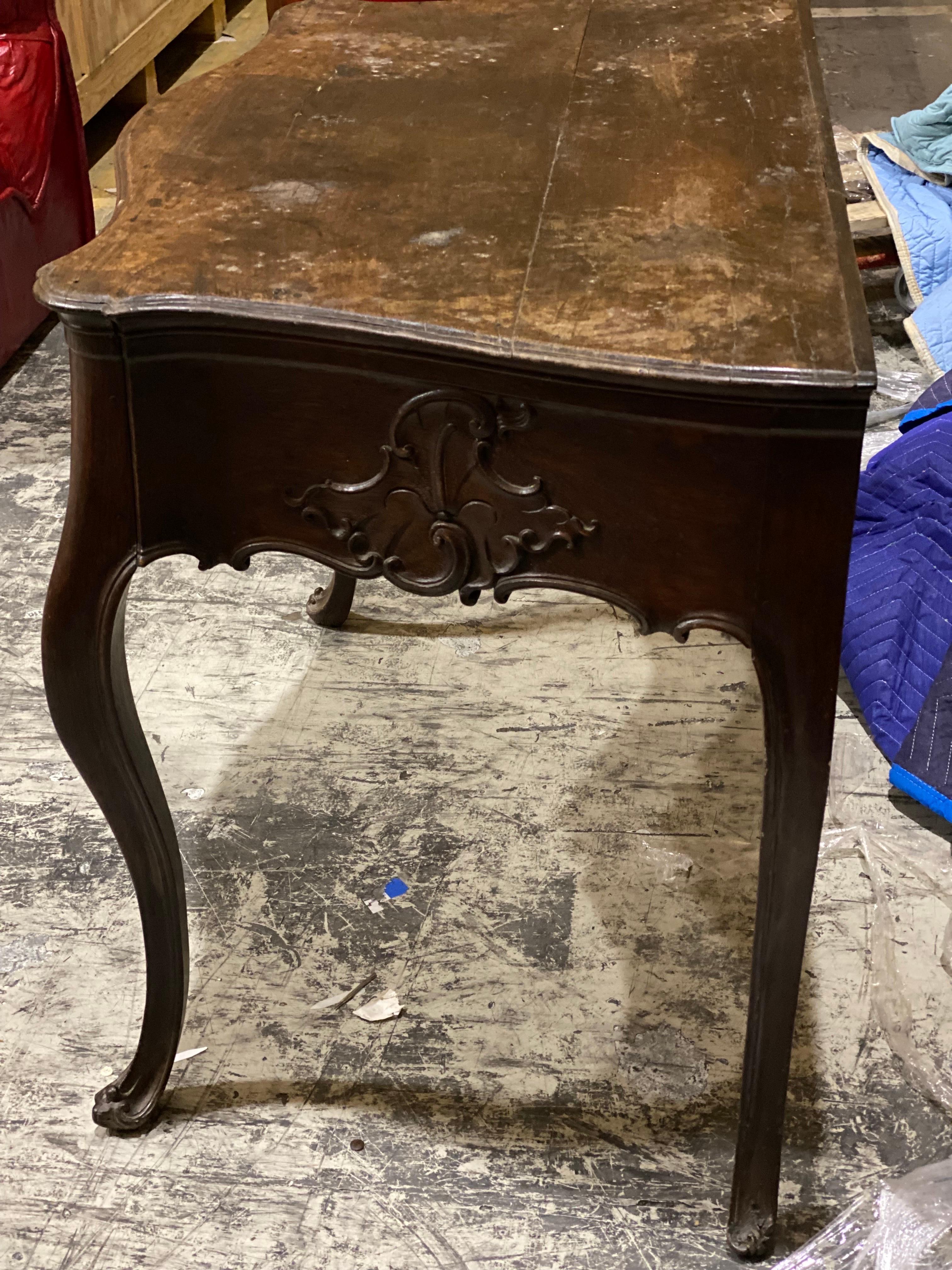 19th C French Louis XV Style Carved Walnut Two Drawer Table
A beautifully carved serpentine shaped table with two drawers and classic Louis XV detailing. Original hardware. Previous restorations visible on front right drawer. Chip on front left