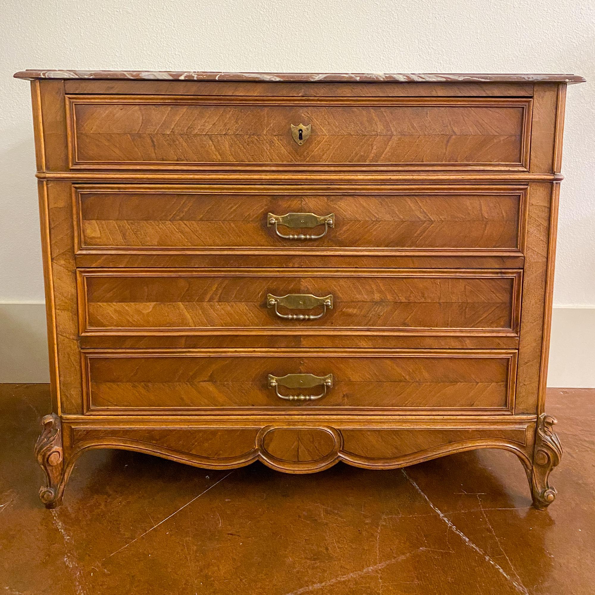 This antique French Louis XV style chest of drawers features beautiful veneer-front drawers, three of which open using the brass bail-pull hardware with the top drawer using a key pull (key included). The drawers are crafted with dove-tail