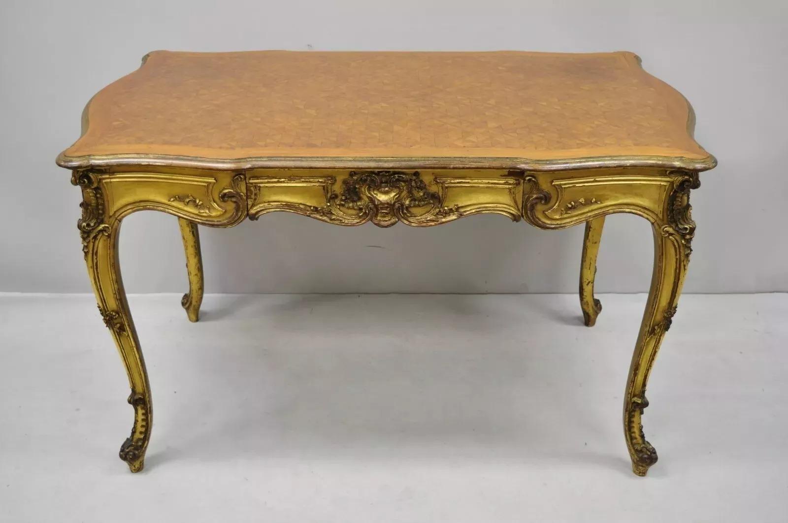 Scrivania in legno dorato in stile Luigi XV del XIX secolo con piano intarsiato. L'articolo è caratterizzato da una finitura dorata e distorta, piano sagomato, intagli su tutti i lati, splendido piano intarsiato, 1 cassetto a coda di rondine, gambe