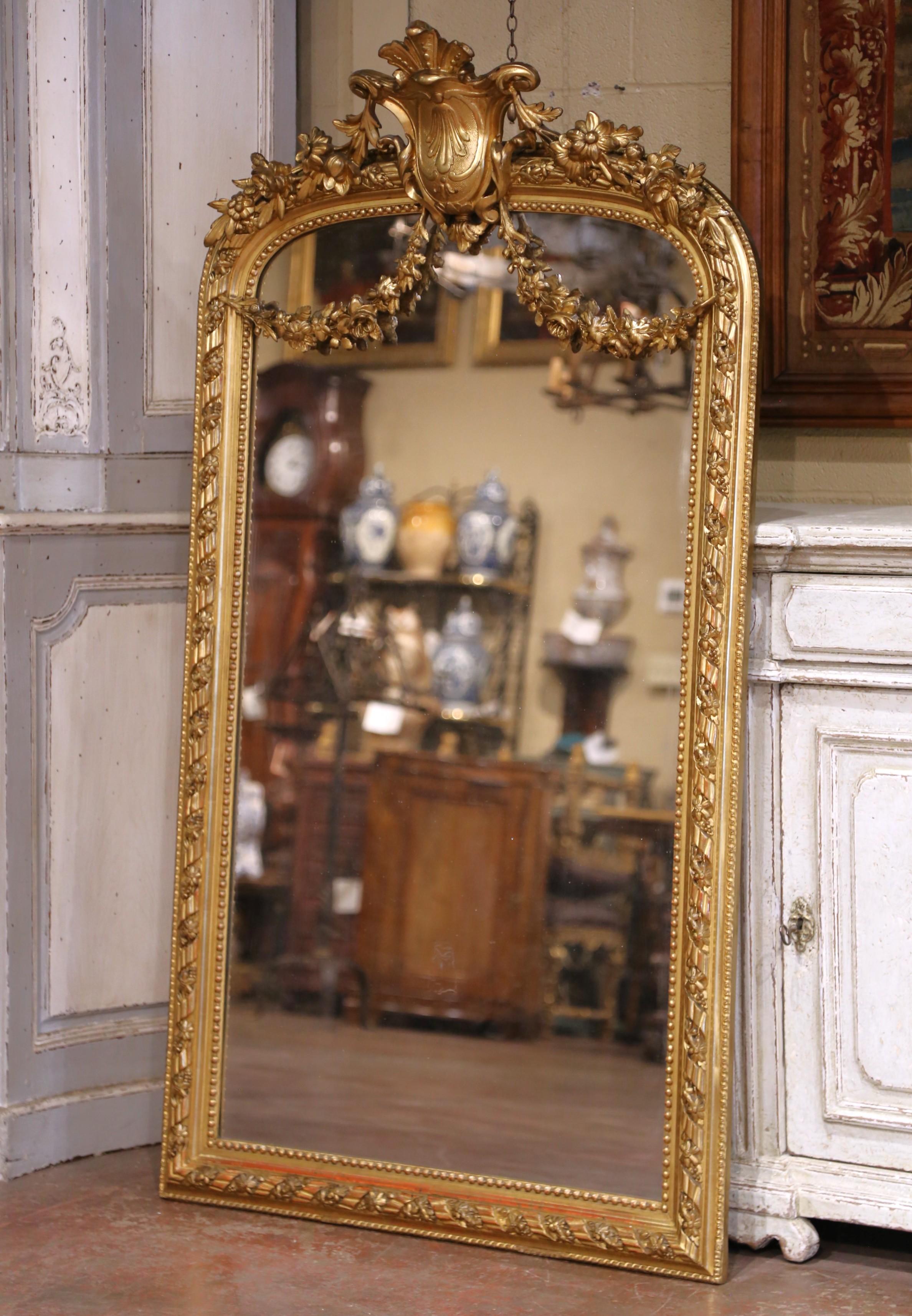 Élevez votre intérieur avec ce grand et élégant miroir en bois doré antique. Fabriqué en France vers 1860 dans le style raffiné de Louis XVI et d'une hauteur impressionnante d'un mètre cinquante, le cadre arqué est couronné d'un écusson sculpté de