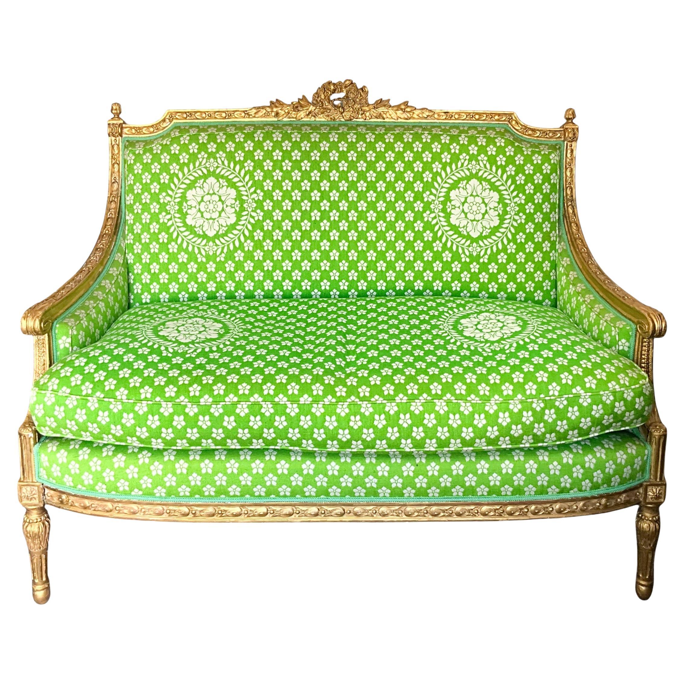 This is such a lovely piece! It is a 19th century French Louis XVI style carved giltwood settee in vintage upholstery. The frame shows some non-offensive chippiness. The upholstery is in very good condition with the exception of two notable stains