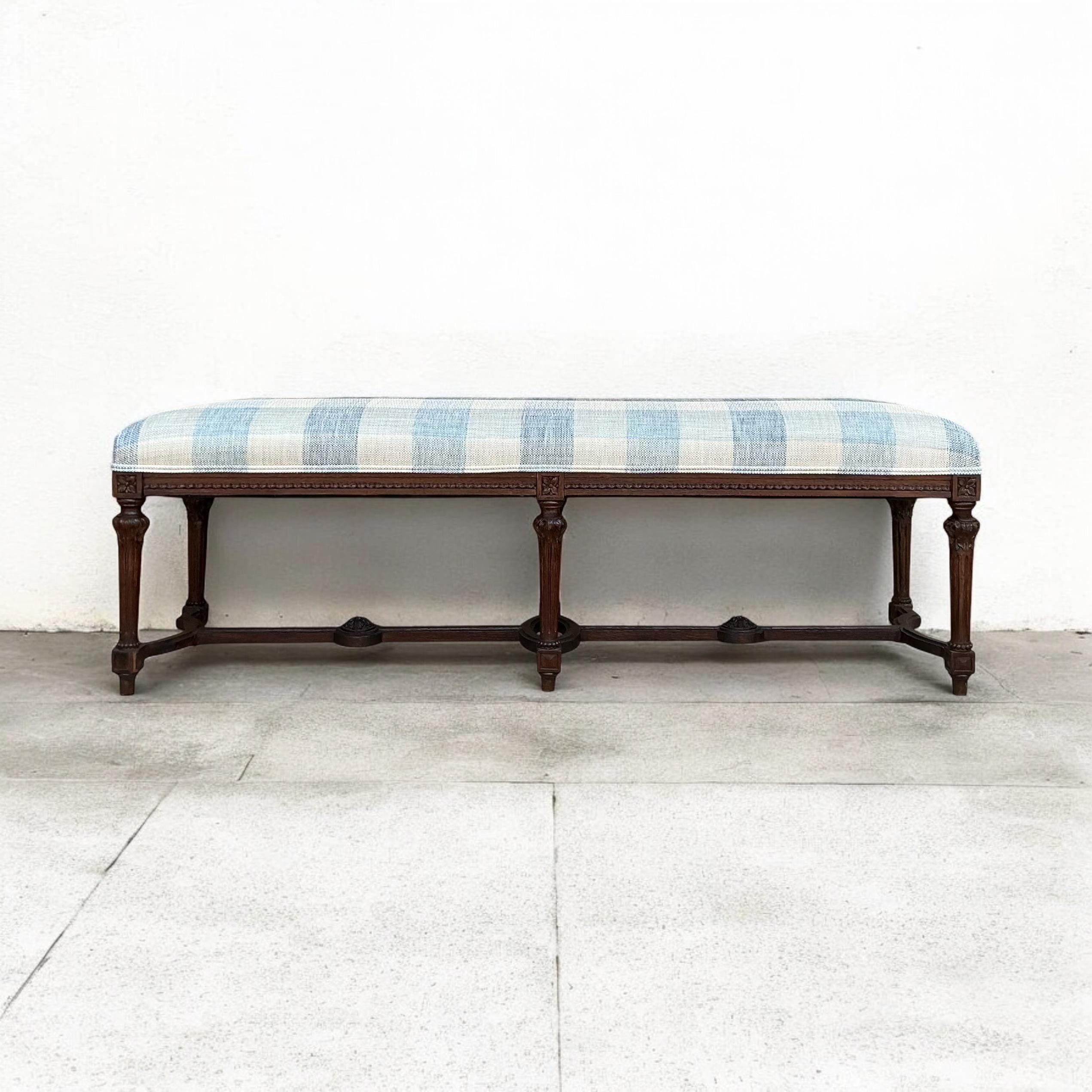 This is a 19th century French Louis XVI style bench that has been newly upholstered in a blue and white check. The carved fruitwood frame is in good condition. 