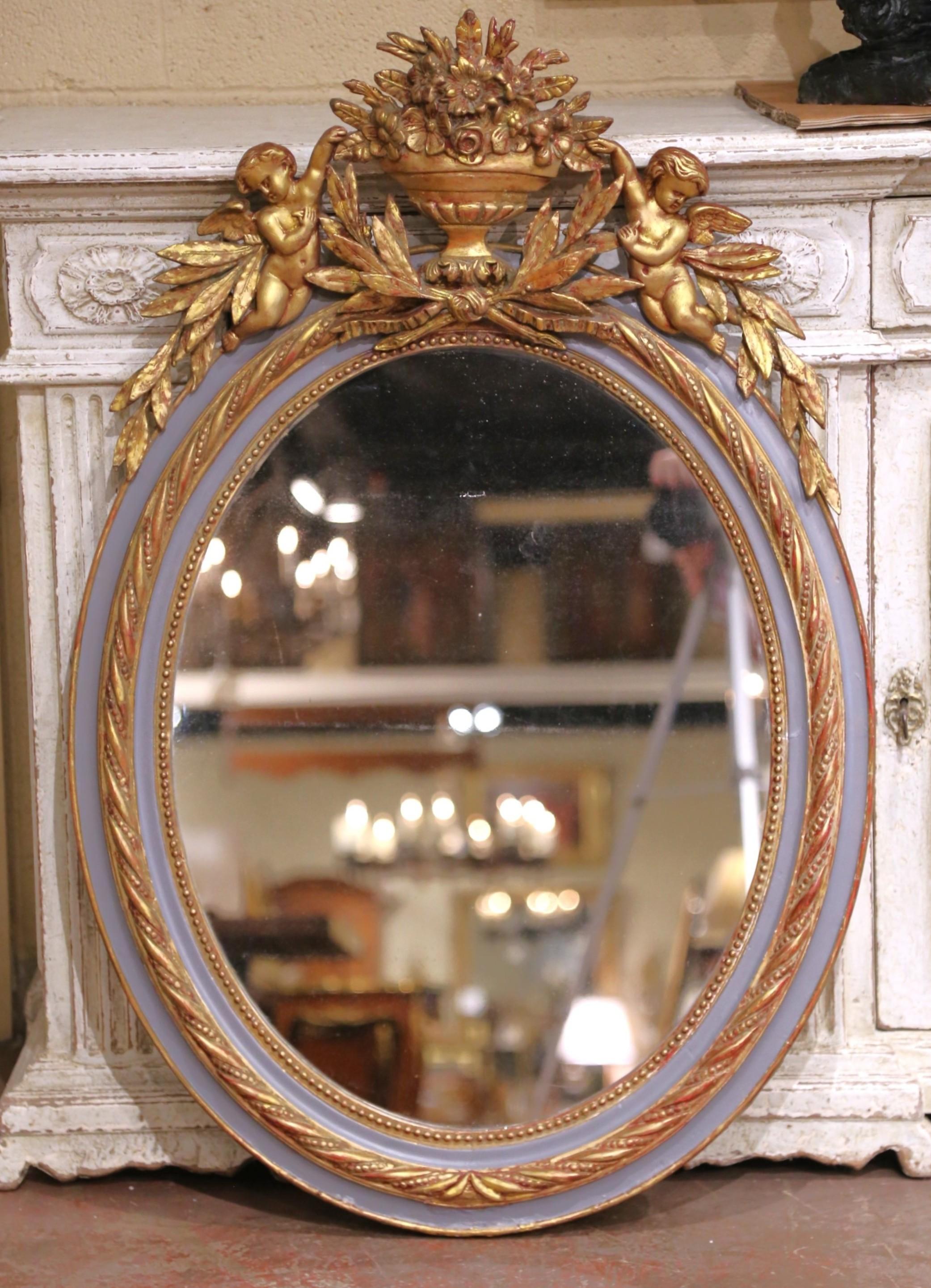 Espejo de pared ovalado dorado y pintado Luis XVI francés del s. XIX con querubines Tallado a mano en venta