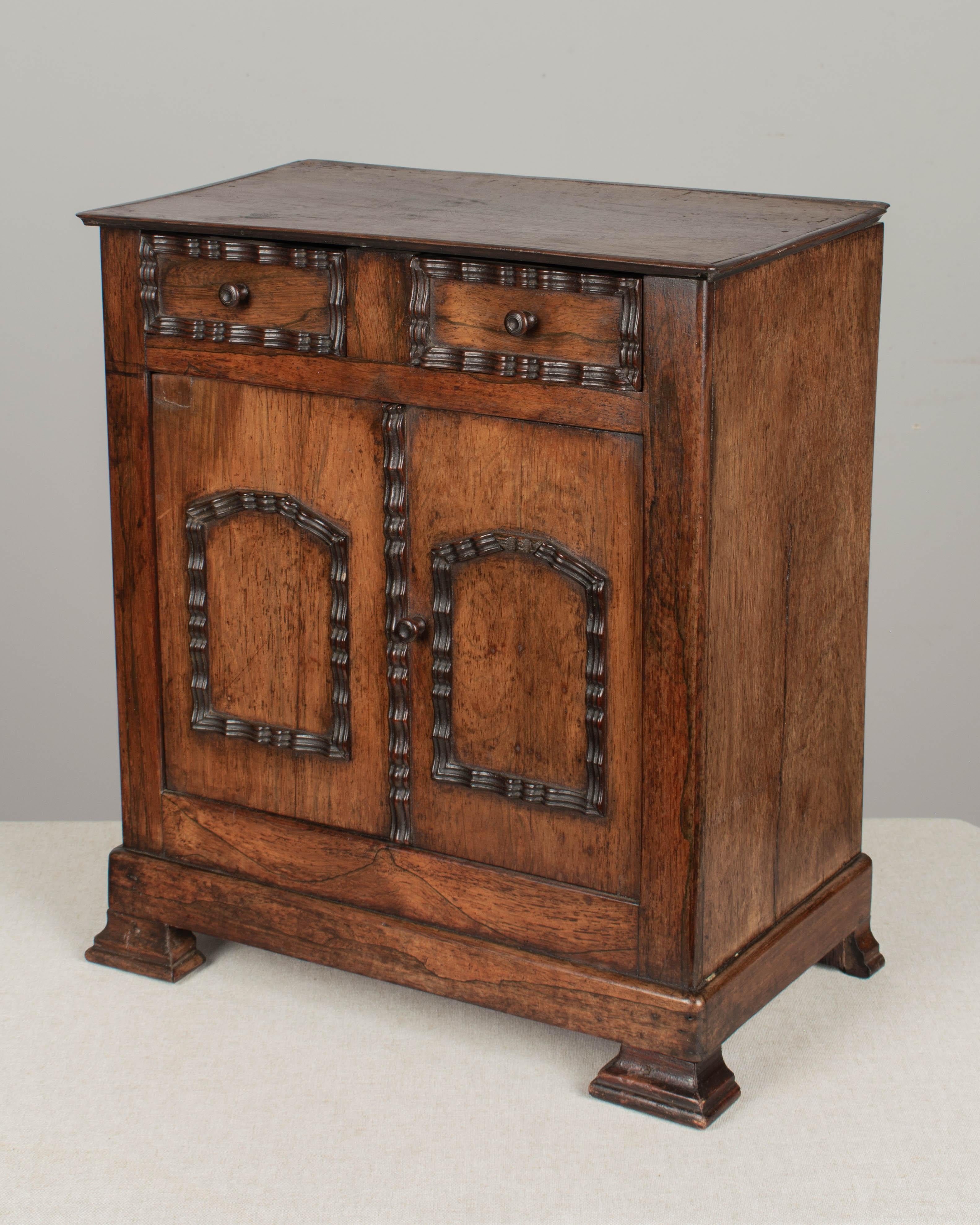 A late 19th c. French miniature doll furniture buffet made of walnut with rosewood trim and oak as a secondary wood. Two small dovetailed drawers above cabinet doors opening to an interior with a single shelf. In good condition with a small split on