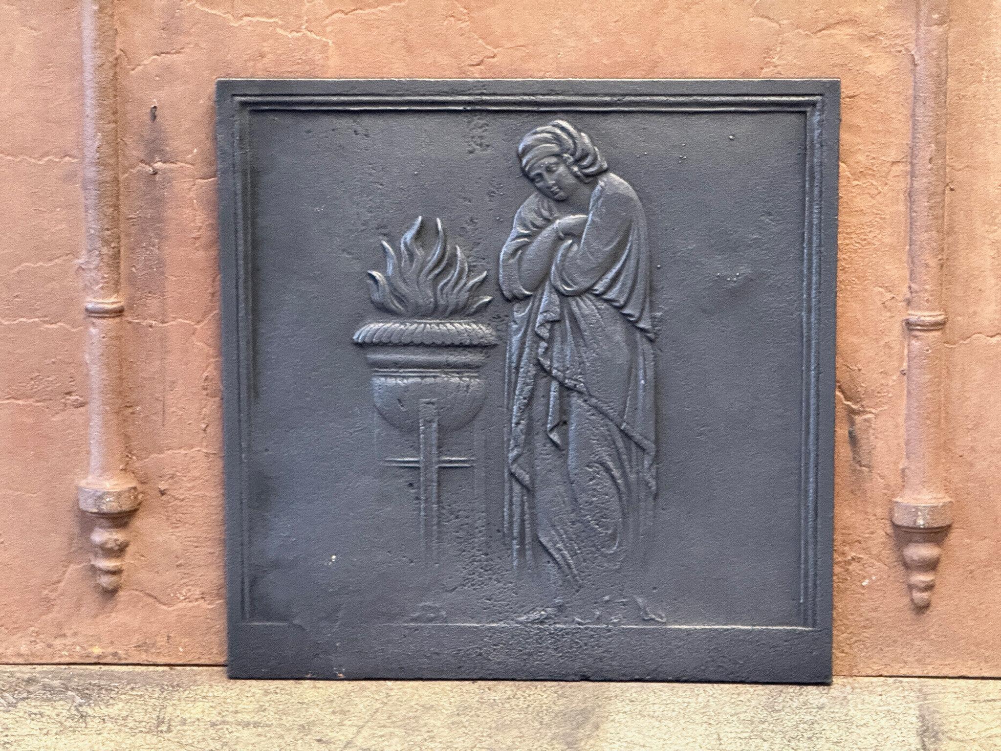 French Napoleon III Period 'Vestal Virgin' Fireback / Backsplash

The fireback is made of cast iron. The patina is black/pewter colored. 

The fireback is in good condition and does not have any cracks.