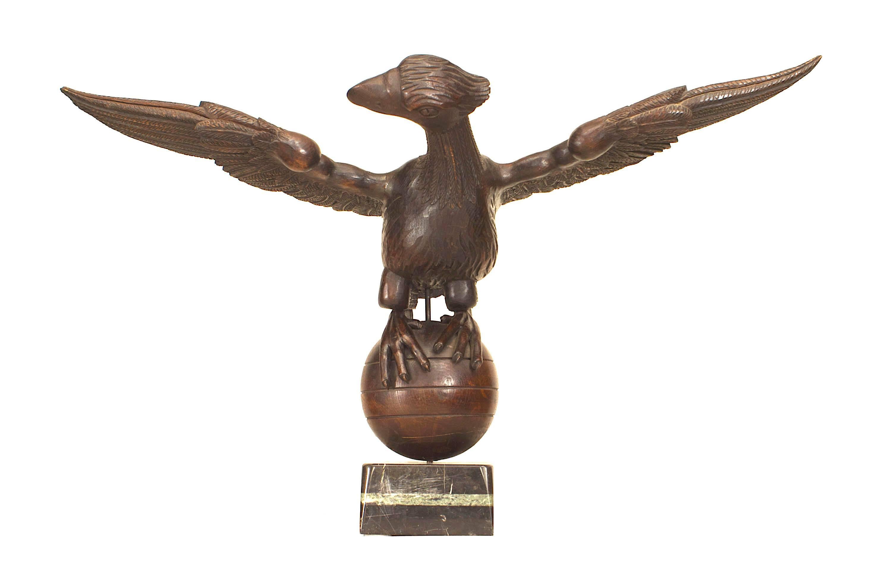 Französische (19. Jh., napoleonische Ära) volkstümlich geschnitzte Eichenholzfigur in Lebensgröße eines Adlers mit ausgebreiteten Flügeln, der auf einer runden Kugel mit Marmorsockel thront.
    