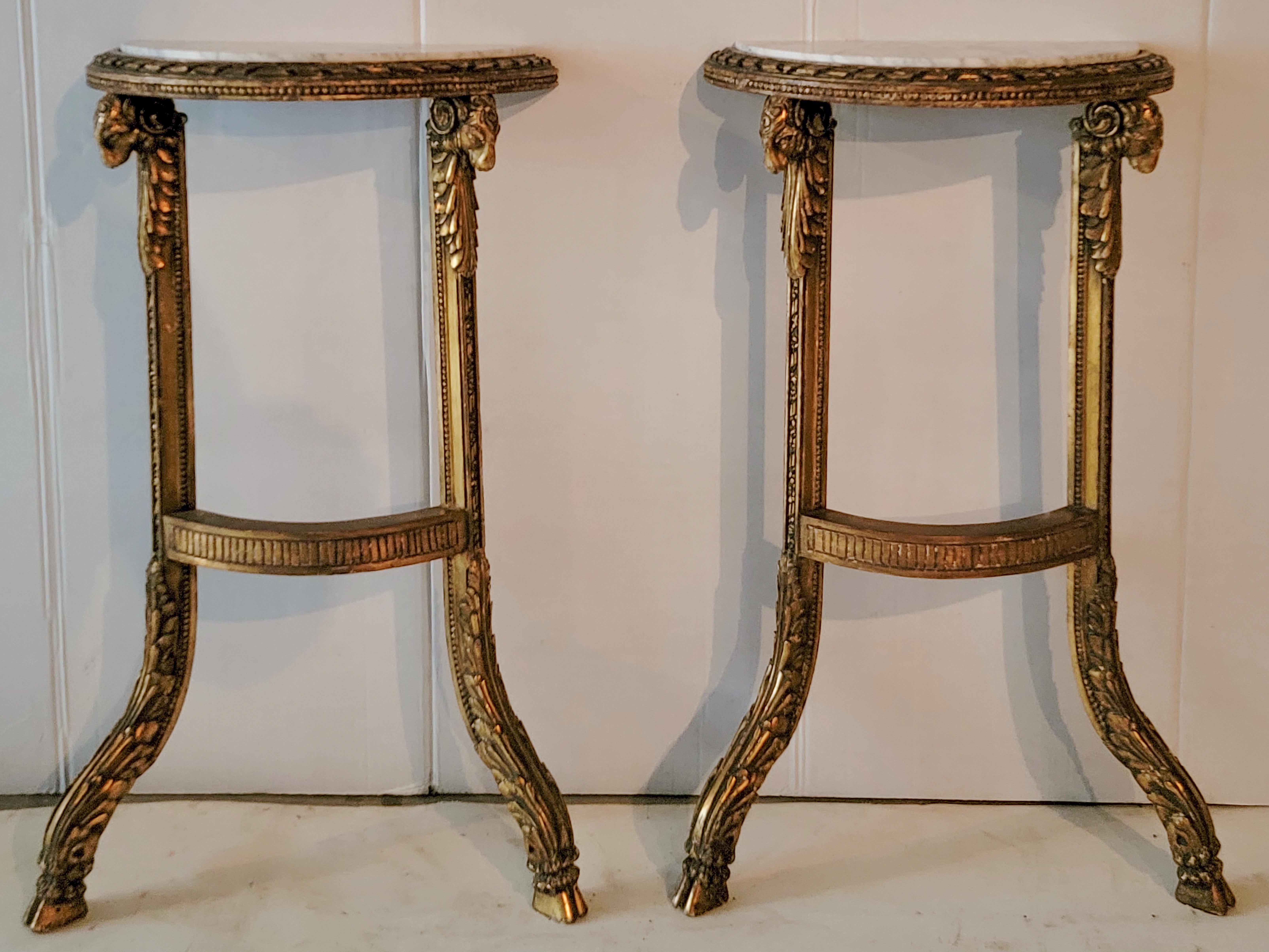 This is a pair of petite 19th century French carved ram marble top console tables. The marble is white with veining. The feet are hairy hooves. They are intended to be wall mounted.