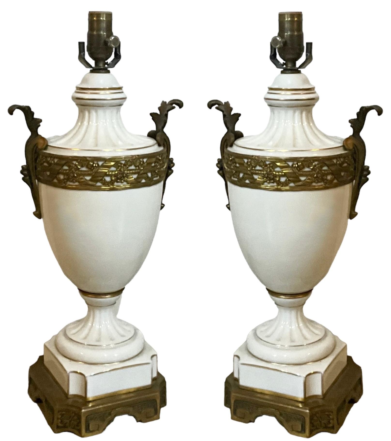 These are beautiful! This is a pair of French neoclassical style white porcelain lamps with gilt and gilt bronze accents. The wiring is new, and I believe they are signed up inside the stem. These have timeless appeal! 