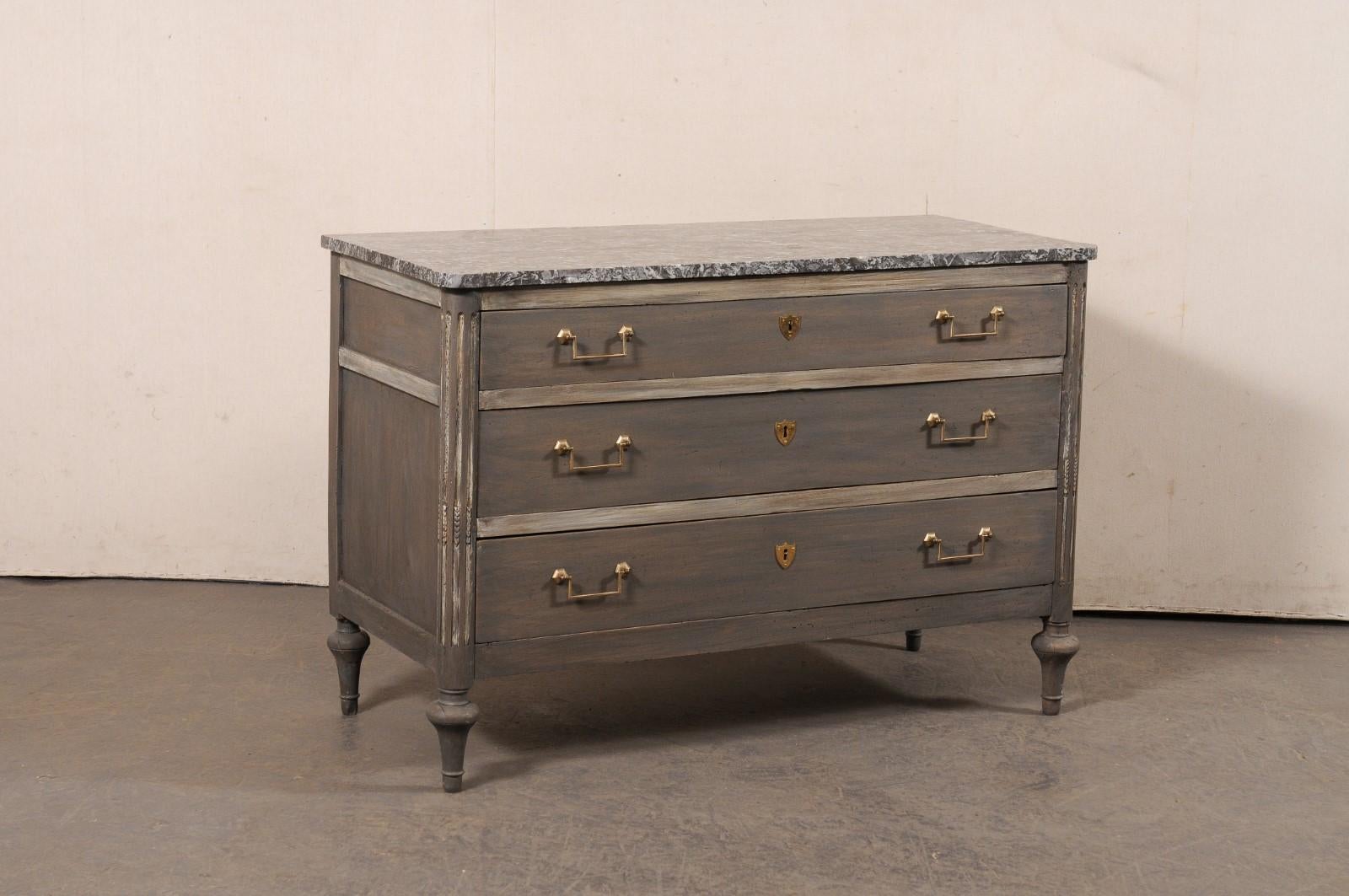 A Neoclassical French carved and painted wood commode, with original marble top, from the 19th century. This antique chest from France features its original marble top with rounded front corners and a subtle reverse breakfront design, atop a