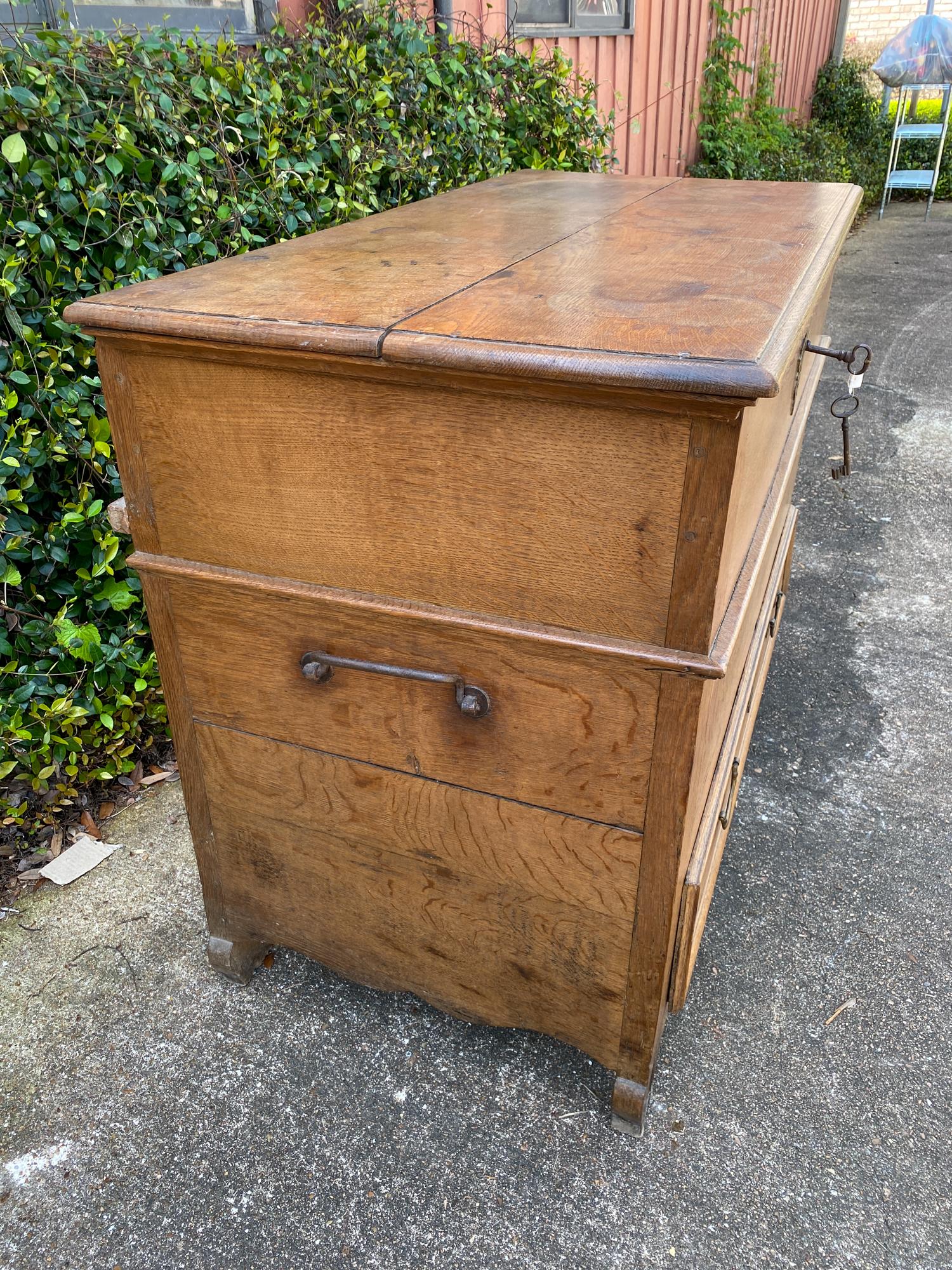 This is a 19th century chest with a hinged top and one lower drawer. Inside the chest is a large compartment accessed by lifting the hinged lid. The key for both the lid and the lower drawer are present and do work in their respective locks. The
