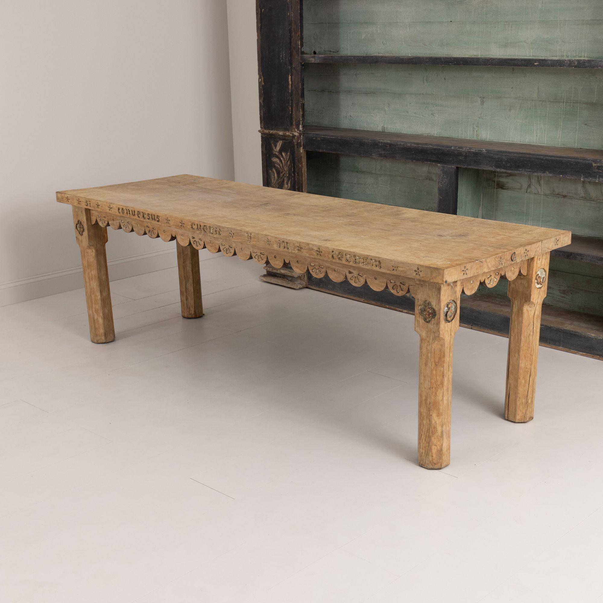 A very charming and distinct French oak rectangular table from the 19th century. The beautiful, aged patina is original. The apron is scalloped on all four sides and features unique Latin carvings. Sturdy chamfered square legs with carved symbols on