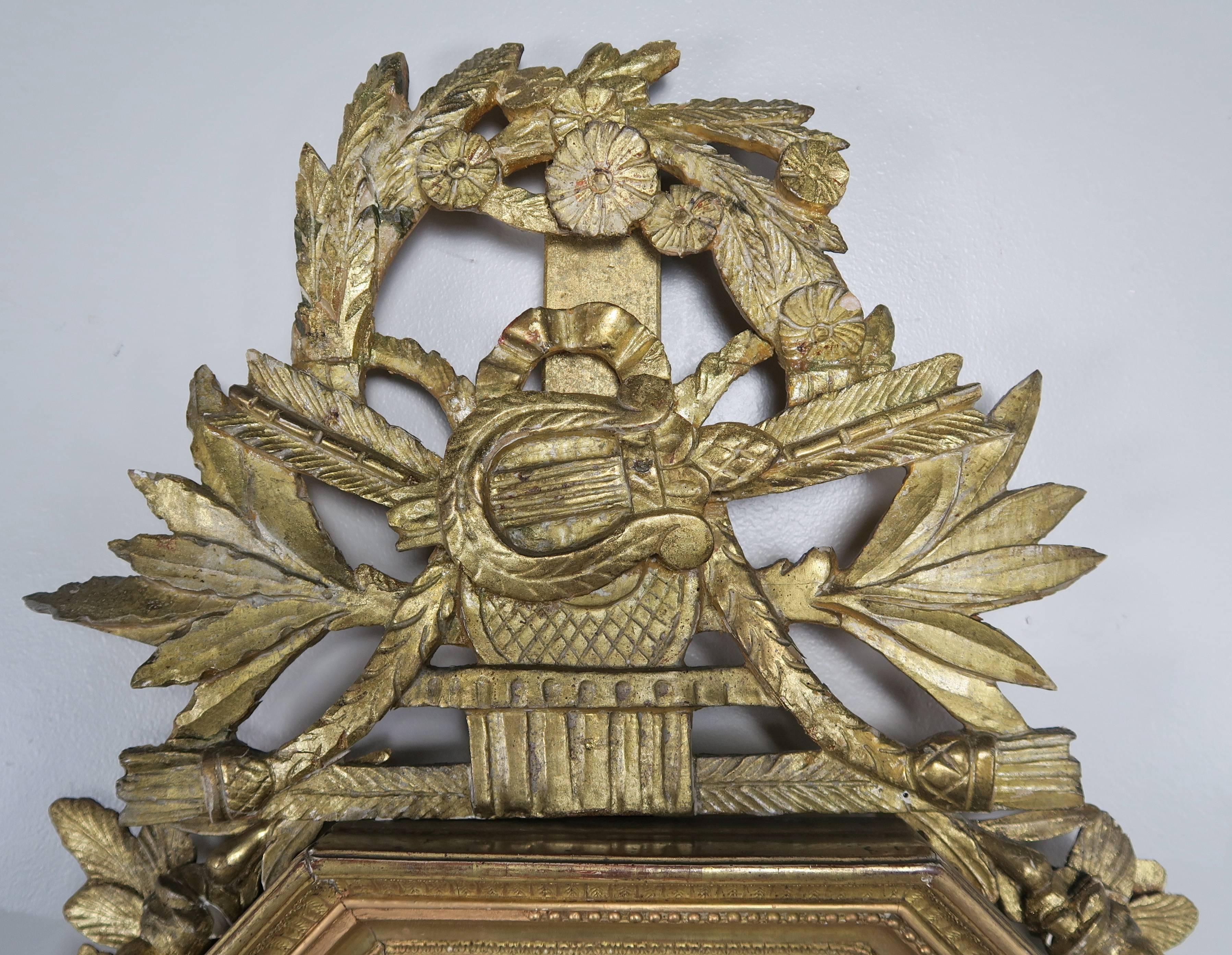 19th century French octagonal shaped carved giltwood barometer with carved beaded moldings. There is a centre harp that is flanked by laurel leaves, tassels and arrows. A floral carved garland drapes over the top and down the sides of the barometer.