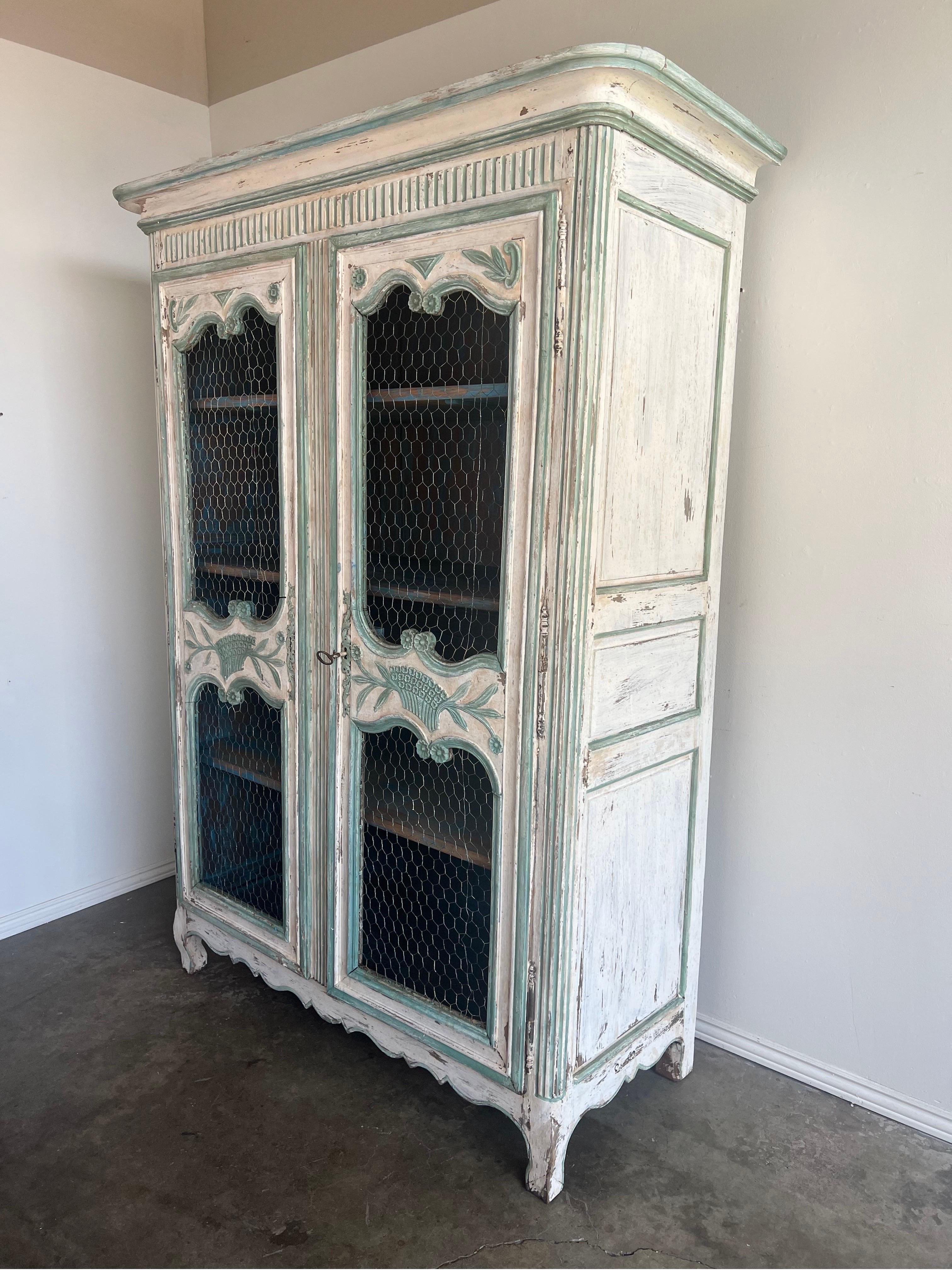 19th C. French painted Armoire w/ chicken wire.  The armoire is painted in shades of aqua marine and antique white.  You can see the wood underneath as well. 
There are two doors that hide three shelves - plenty of storage.  Original brass hardware.