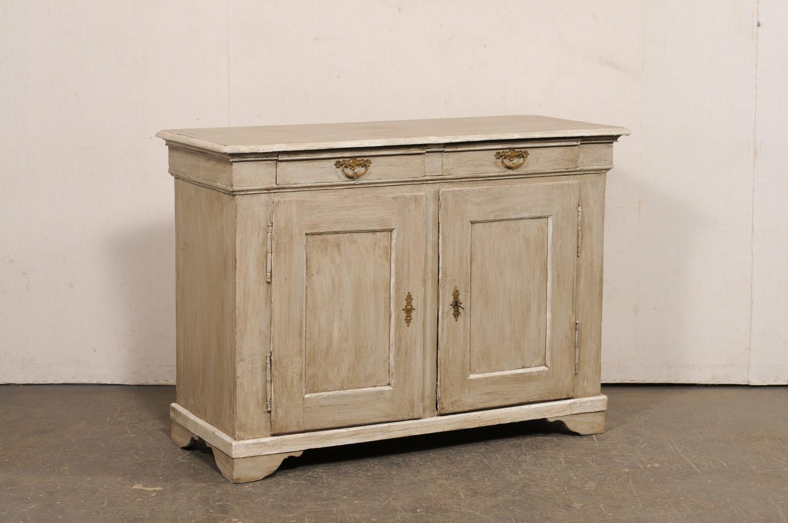 Un mobile buffet francese a due ante in legno dipinto del XIX secolo. Questo mobile antico proveniente dalla Francia ha un piano di forma rettangolare, che sporge leggermente dalla cassa, e ospita una coppia di cassetti più piccoli incastonati nel