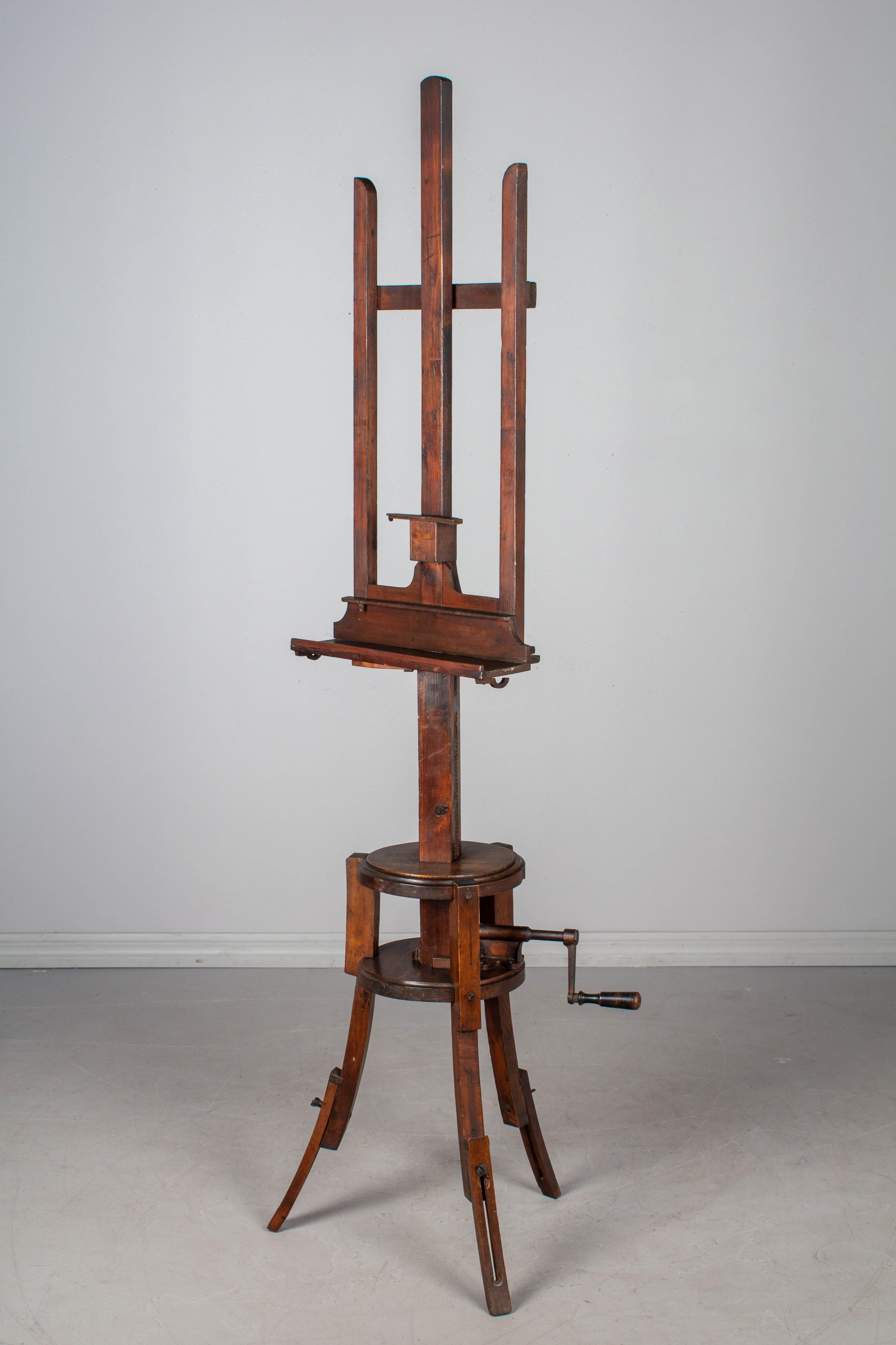 A 19th century French painting display easel with unusual circular base. Made of solid walnut and beechwood with cast iron crank and gear mechanism. Tripod legs with adjustable extensions. Sturdy and well crafted. All original and in working