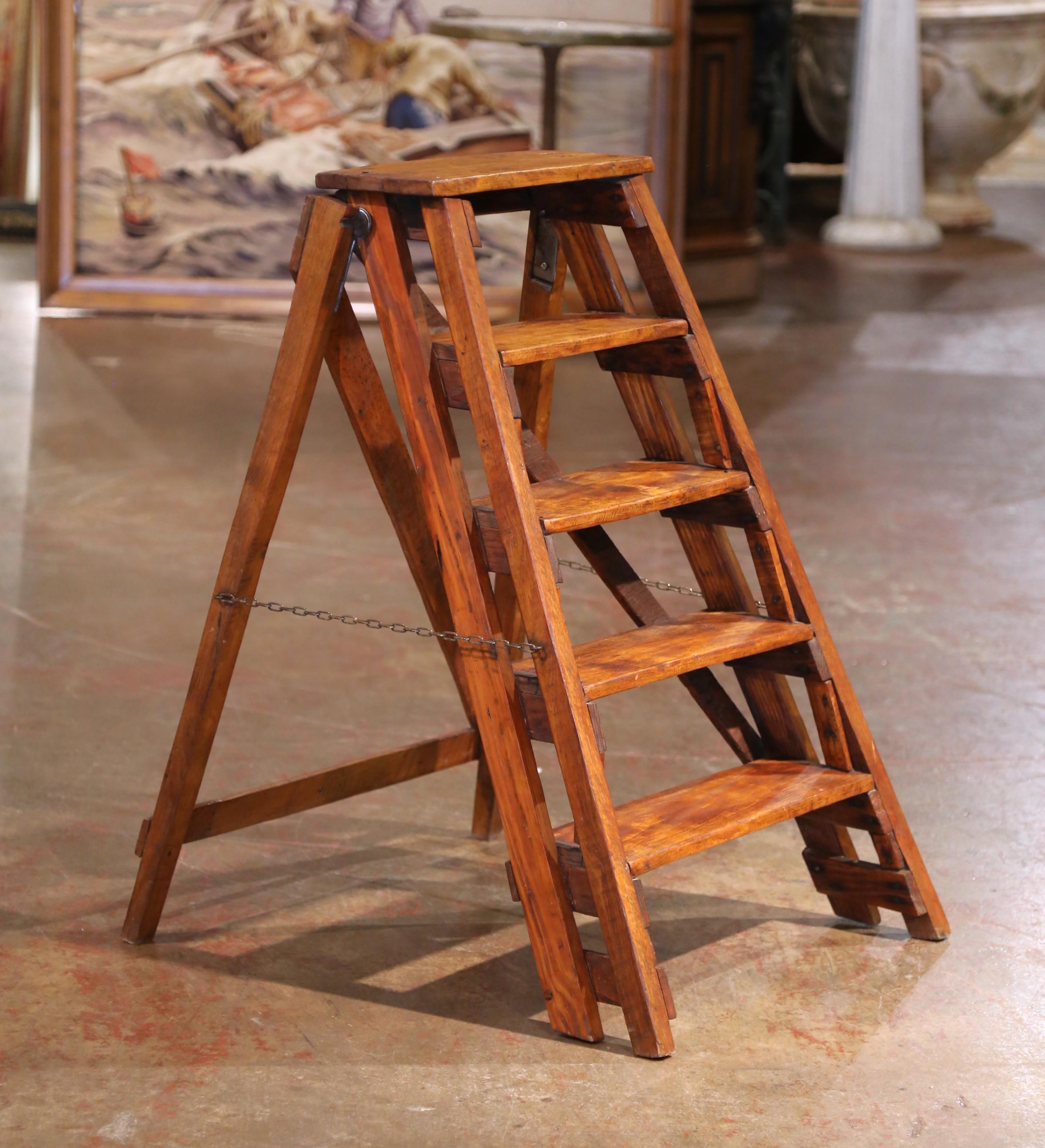 Crafted in France circa 1870, this five-step folding ladder is made from poplar and pine with a warm, timeworn patina that reflects its utilitarian past. The broad top platform reaches 35.5 inches high, supported by gently tapered legs and secured