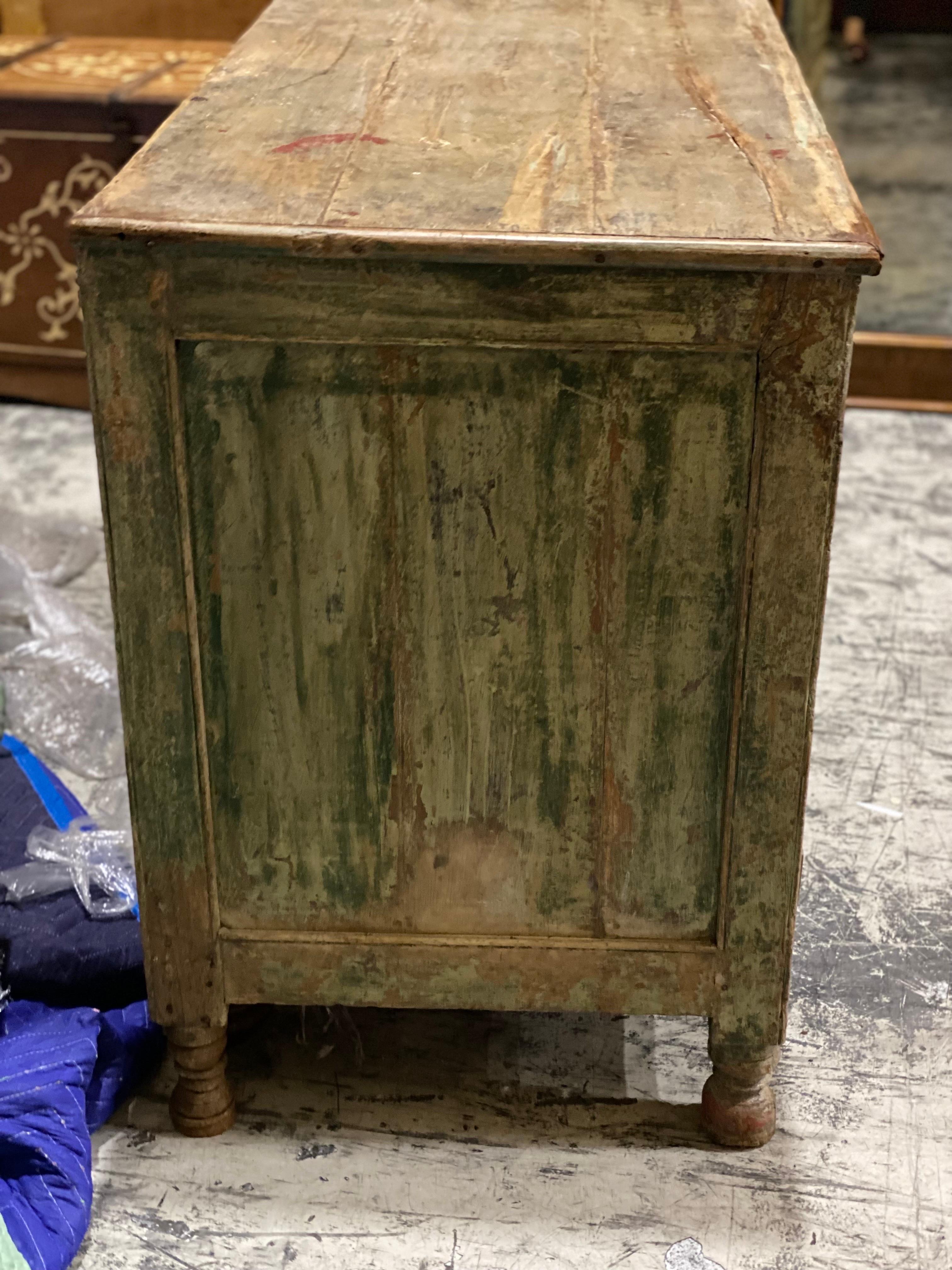 19th C French Provincial Green Painted Carved cabinet 
An unusual carved oval medallion motif with a beautiful aged green patina. One central door and three drawers underneath. One leg slightly uneven but good stable condition. Wear throughout