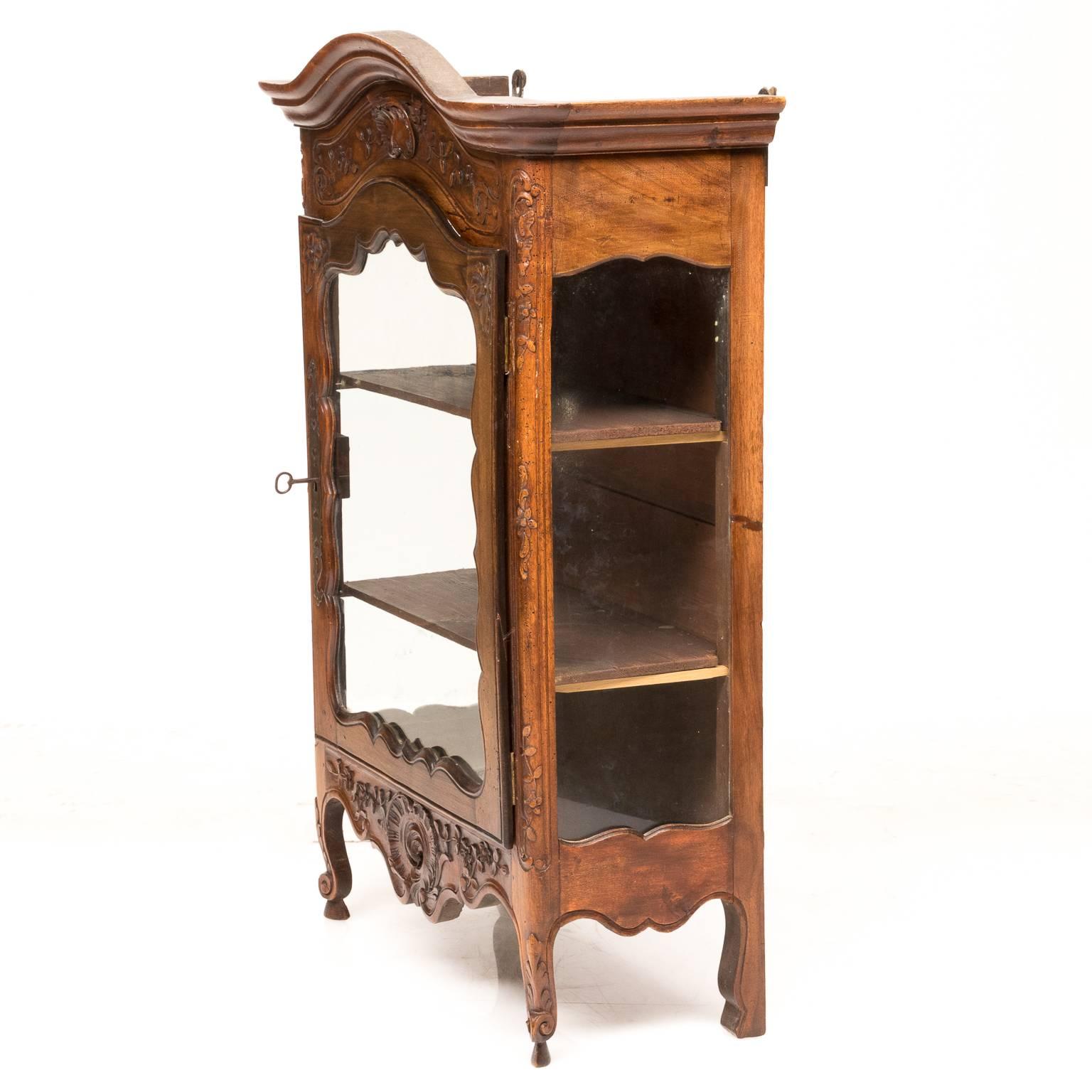 A 19th century French Provincial walnut hanging cabinet. Very well carved, original glass and was lined with fabric (but we removed). The key is present and functional. A quality piece for French country lovers.