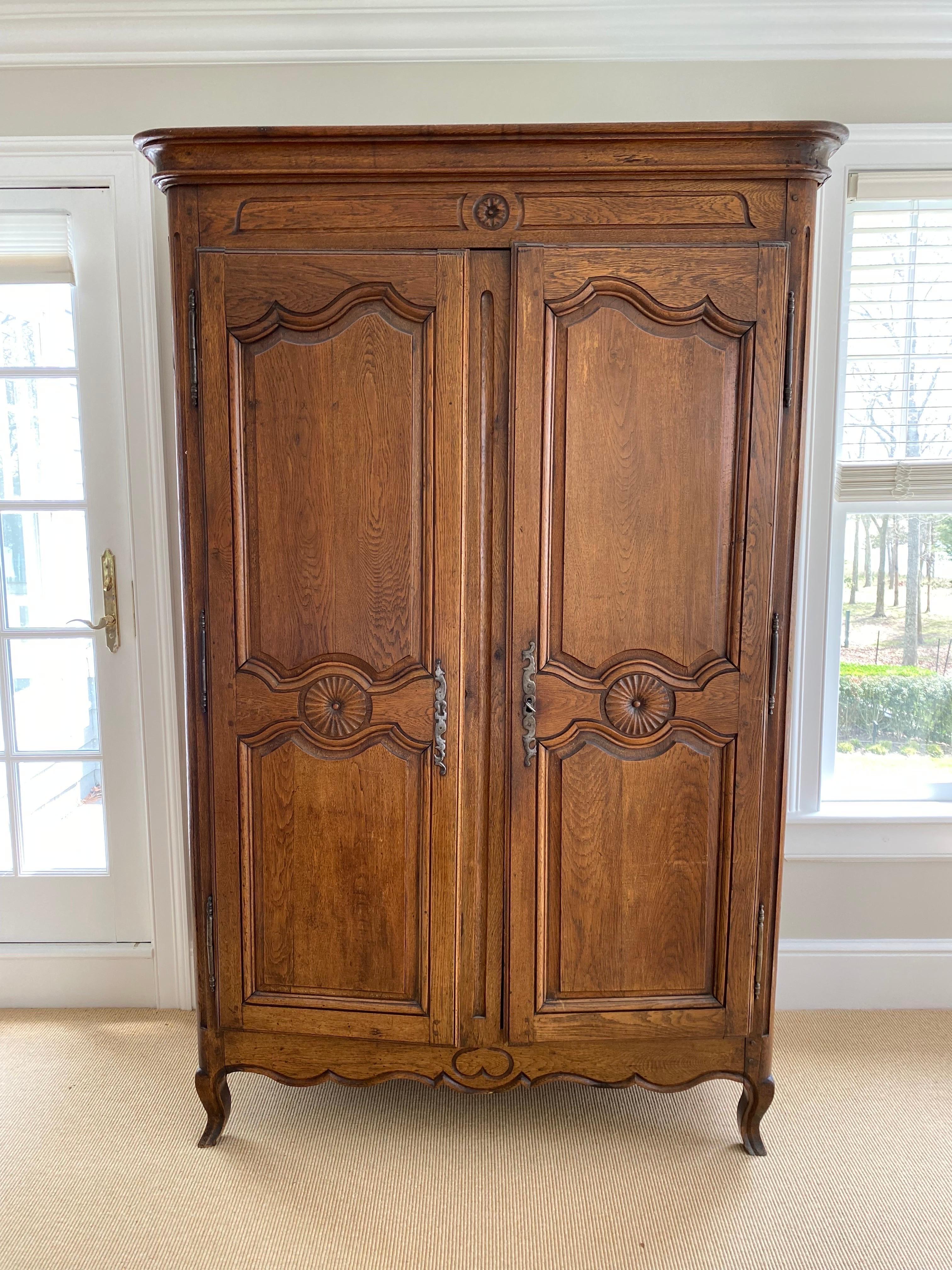 19th C. French provincial oak armoire.
A charmingly carved armoire in oak with central round medallions on the center crown and doors. A later carved heart on the center bottom adds a nice touch, sitting on cabriole legs. Two doors open to two