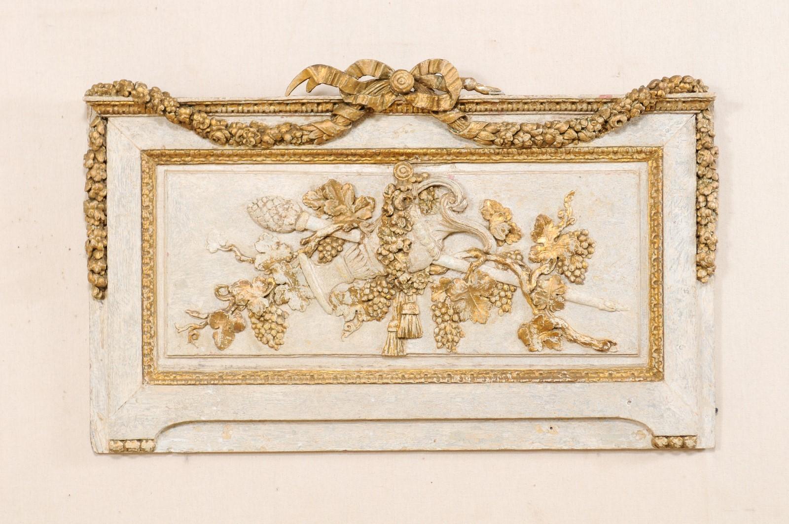 A French wood carved decorative hanging wall plaque from the 19th century. This nicely carved wall decoration from France is rectangular-shaped, and features a three dimensional hand carved ribbon at top crest, with floral swags hanging down