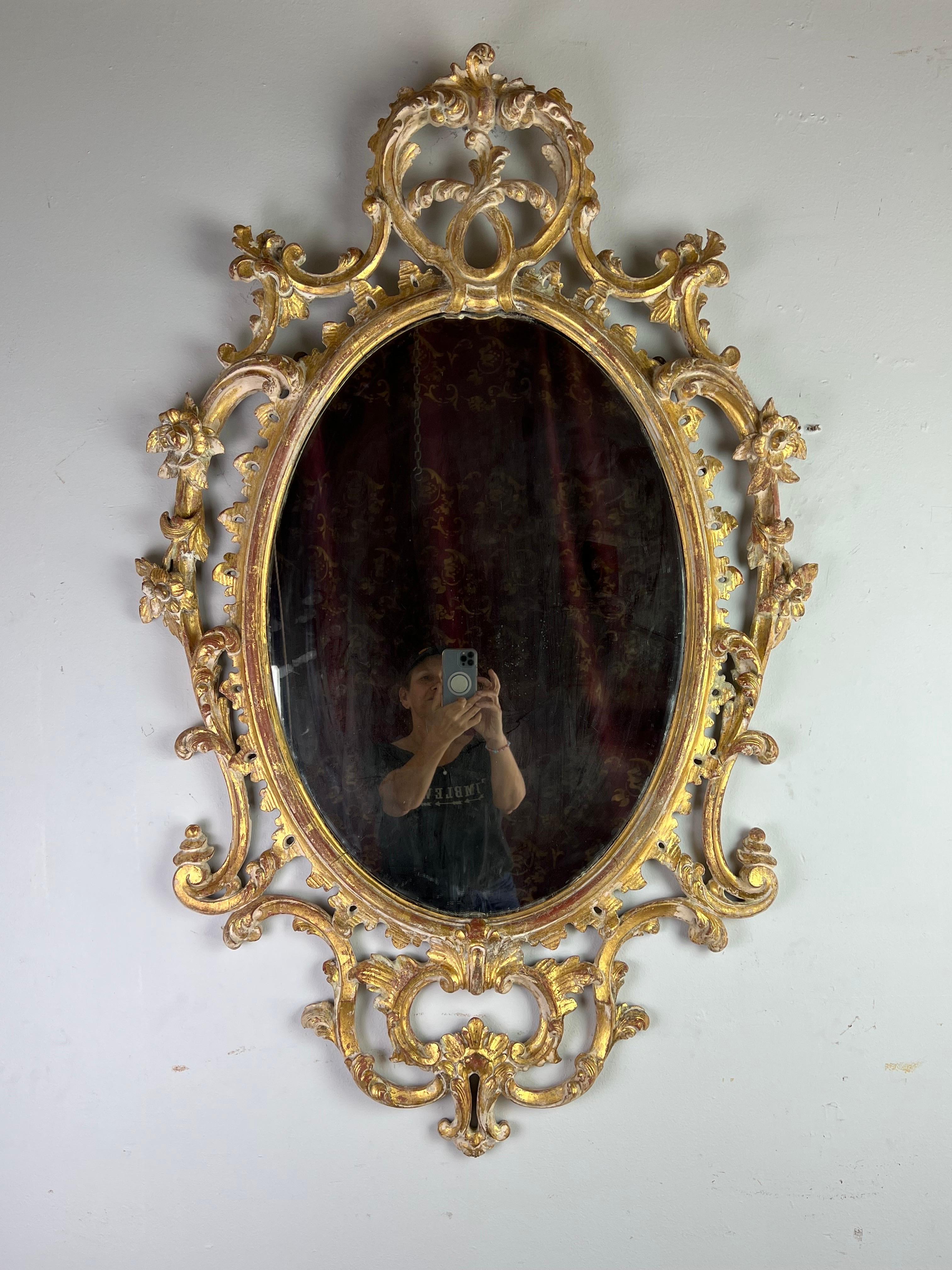 19th century French Rococo style gilt wood mirror. The frame has carved flowers and acanthus leaves throughout. Distressed gold leaf finish with exposed wood.