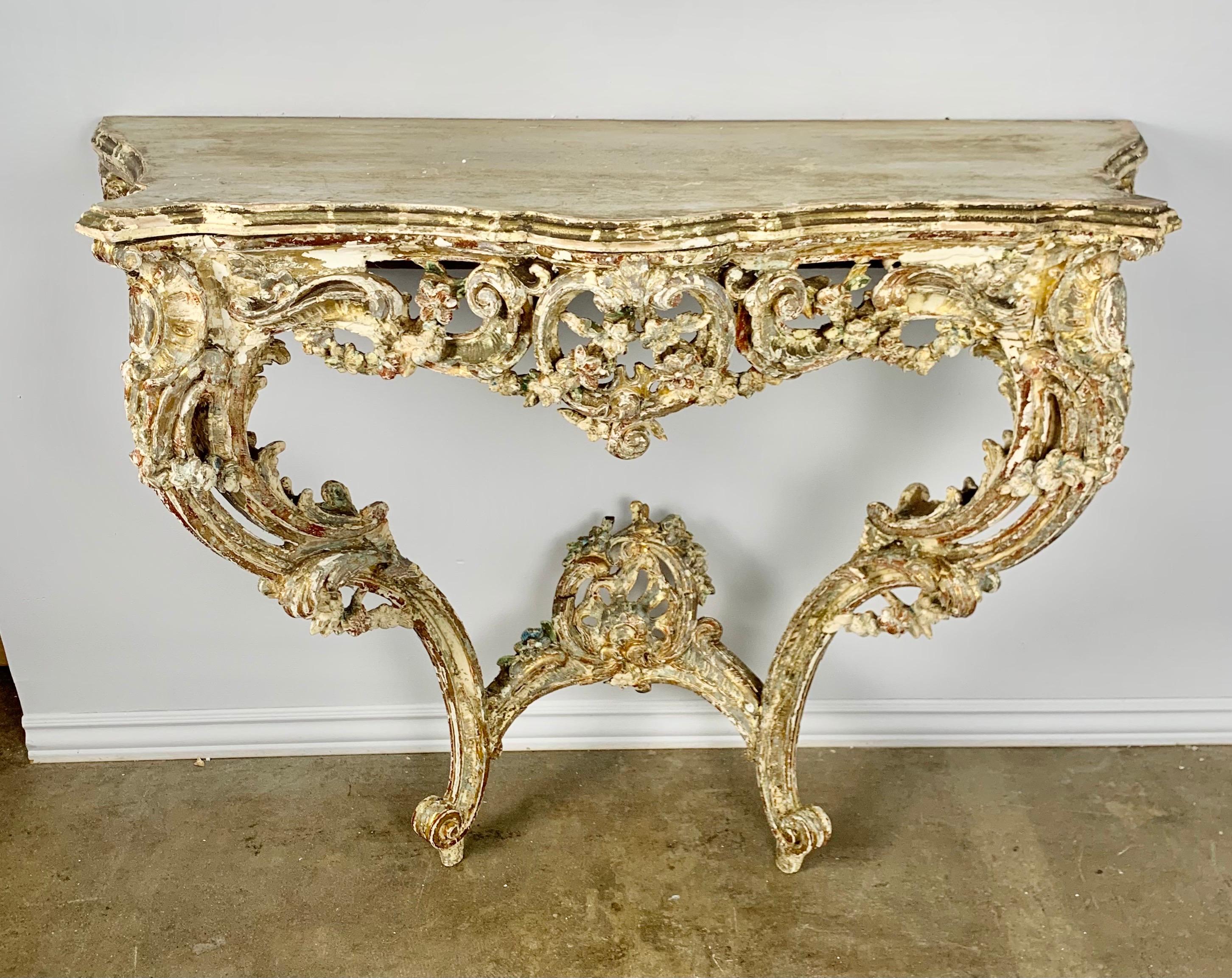French Louis XV style painted & parcel gold gilt console standing on two cabriole legs connected by a center stretcher with finial. The finish is beautifully worn, showing the wood underneath. Wood Top.