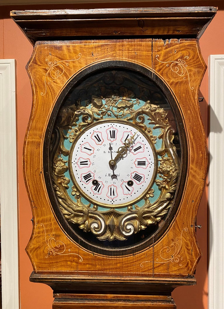 A fine faux bois grain painted pine case comtoise or morbier tall clock of a grand scale with porcelain enameled clock face with Roman numeral dial and calendar, signed by the clockmaker “B. Bignon, à la Martigné”. This clock features an automated