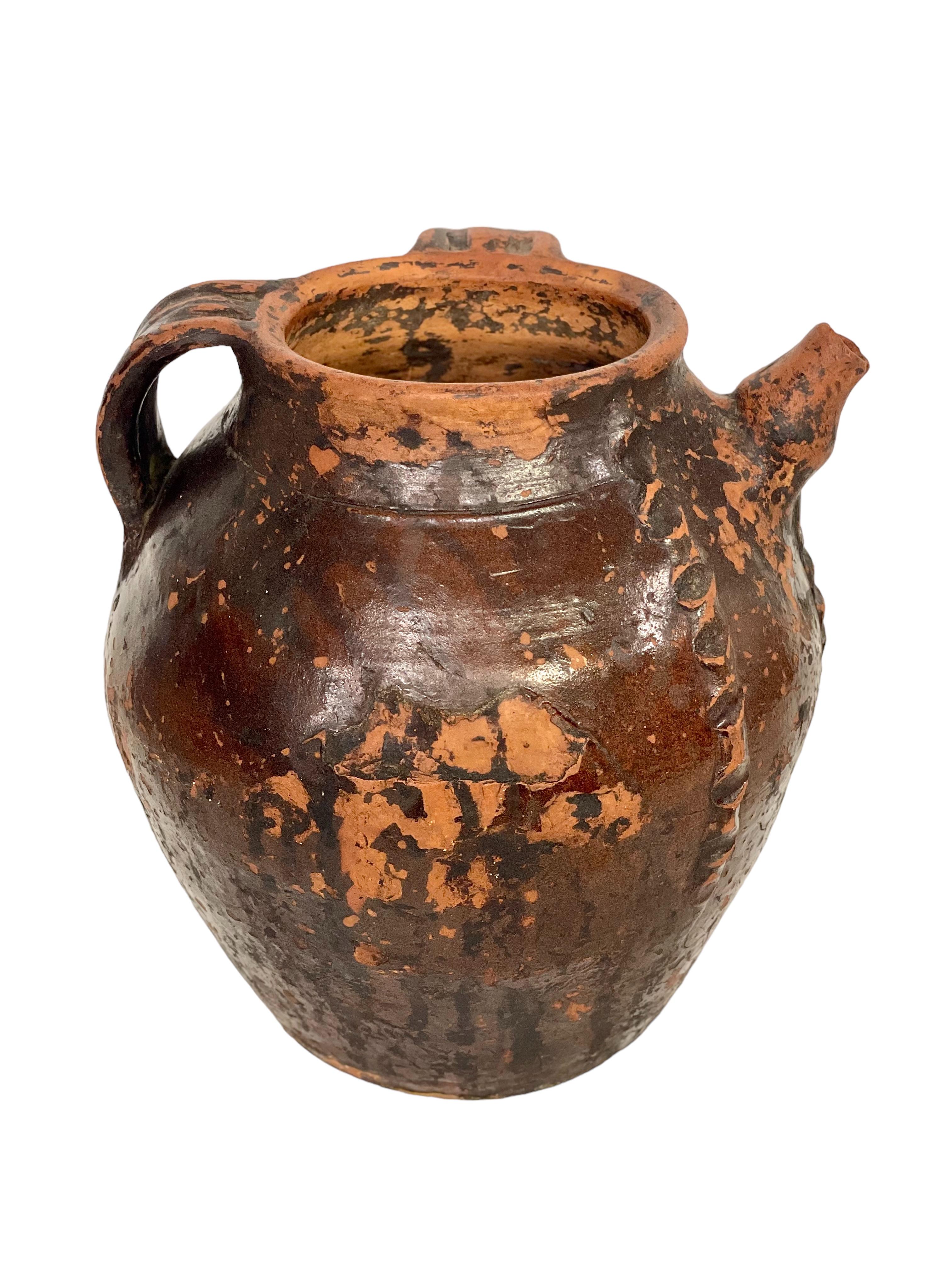 A large and very handsome glazed terracotta walnut oil jug, dating from the 18th century and originating from the south of France. Featuring two side handles and a single pouring spout, this beautiful vessel is covered with a gorgeous