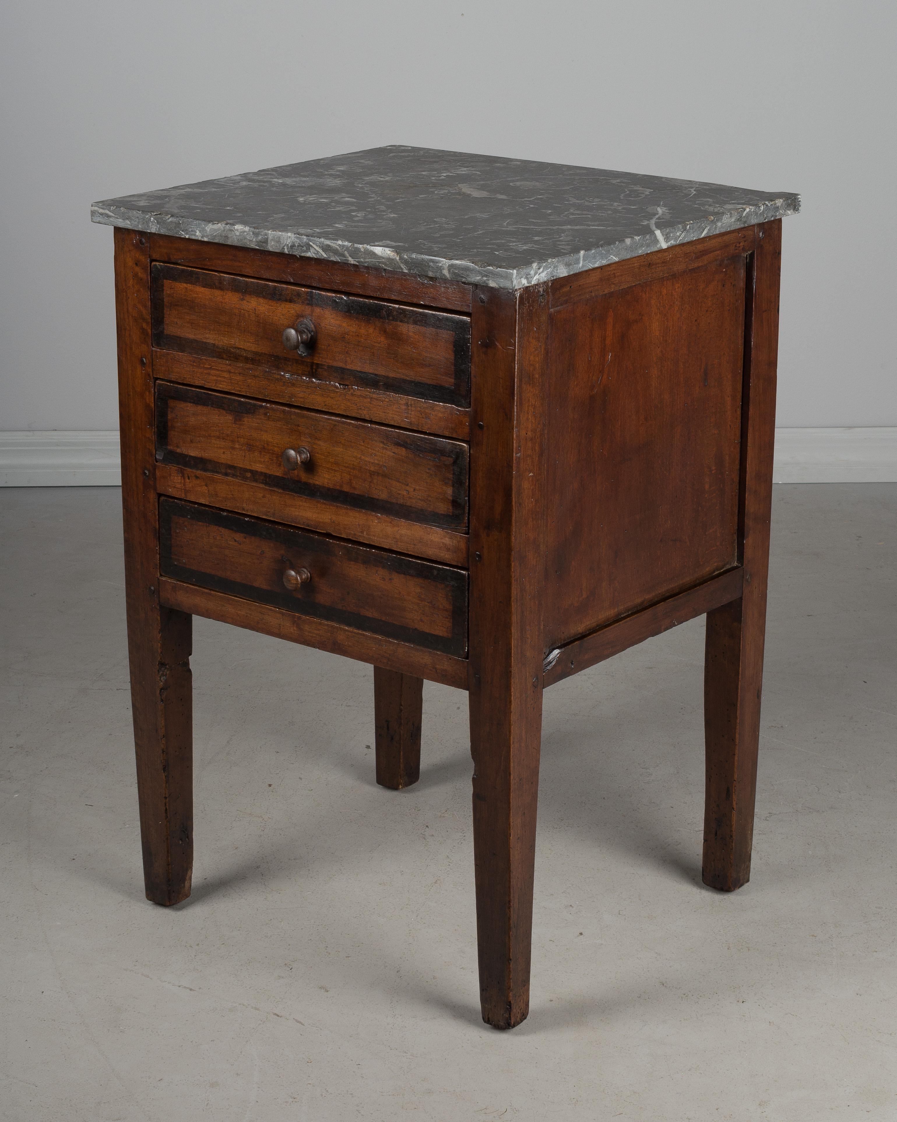 An early 19th century Country French side table made of solid walnut and finished on all four sides. Three dovetailed drawers with replaced wooded knobs. Original grey marble top is not attached. There are a few chips to the edges of the marble.