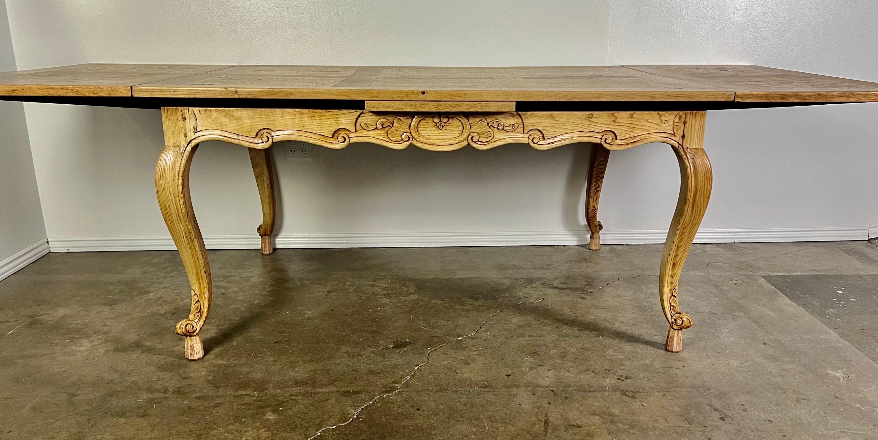 19th century French Provincial style white oak & burled walnut dining table with two leaves. The French table stands on four cabriole legs with rams head feet. There is a simple scrolled design on the apron of the table base. The top has a geometric