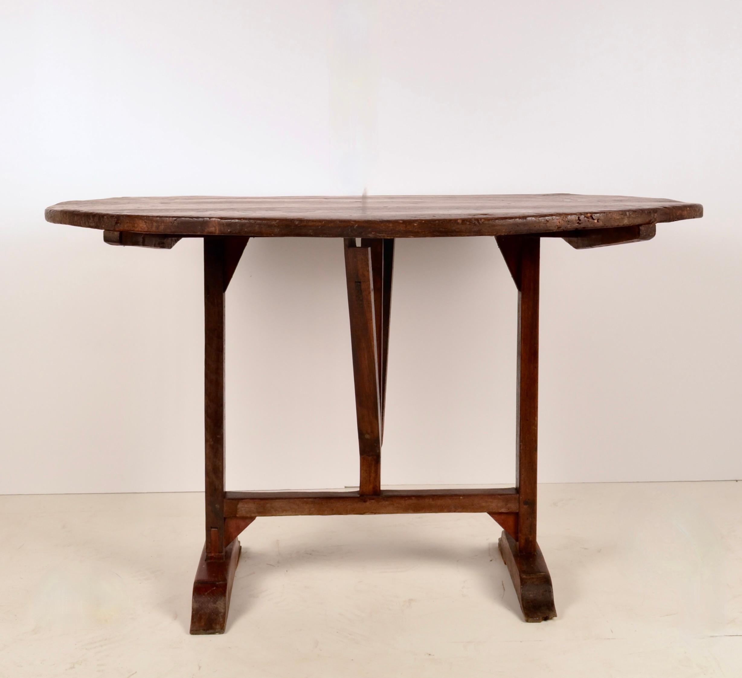 A fine vintage example of a traditional French wine tasting table in oak. The tilting top and swing base allow the piece to be easily stored but drops to be a sturdy table. This table has the traditional base in good condition, and a beautiful