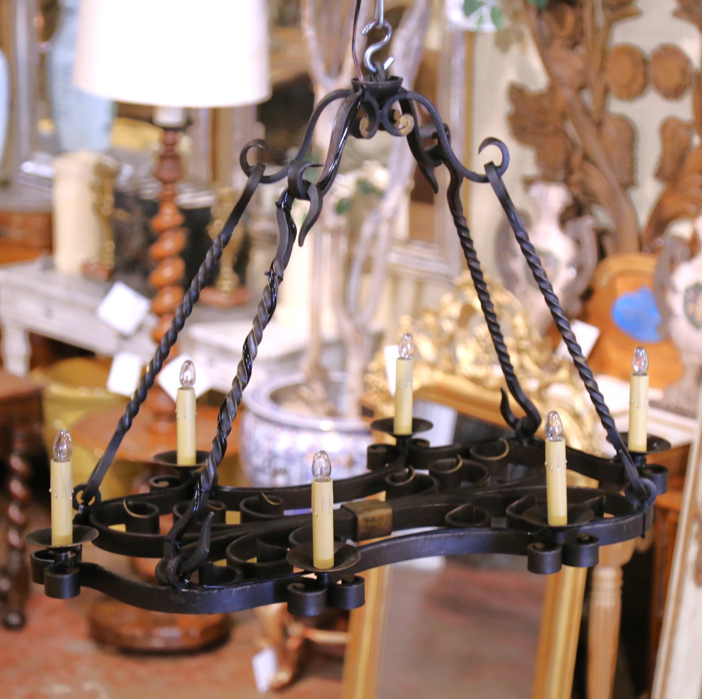 Bring timeless French craftsmanship into your home with this elegant hand-forged chandelier. Crafted in France circa 1880, the six-light fixture features an elongated oval frame adorned with intricate scrollwork and decorative curls. Each light sits