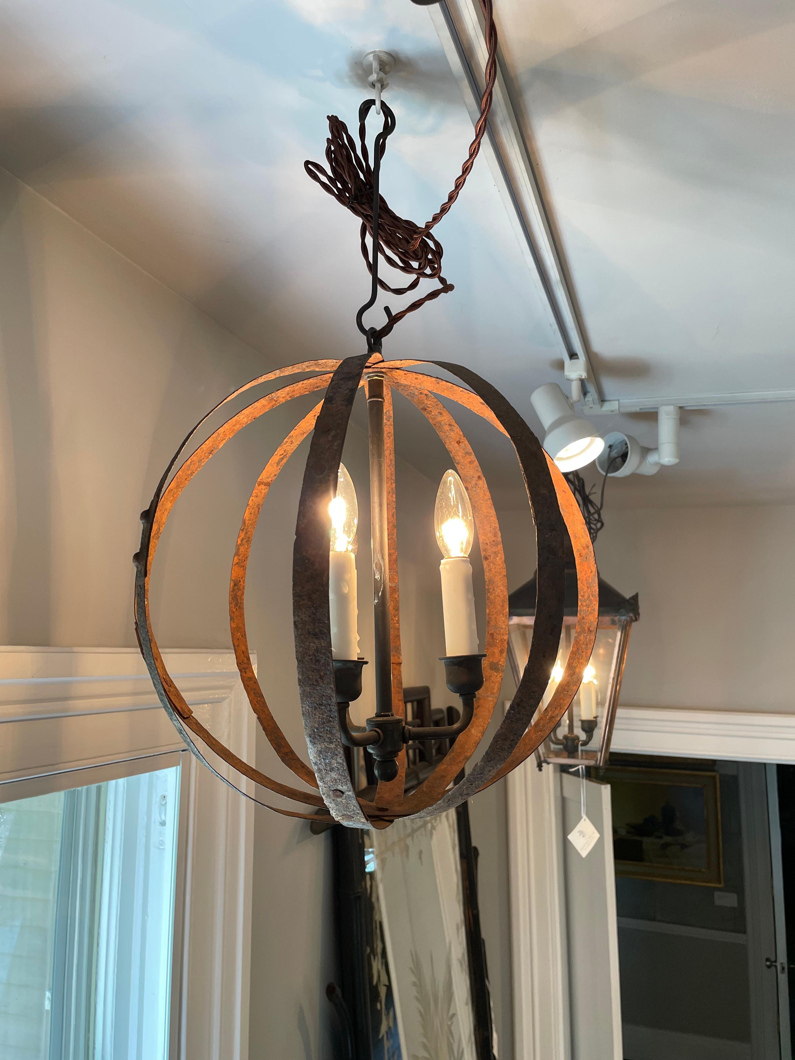 We are always on the lookout for unusual hanging lights and this one is stunningly different. Handmade of 19th C French wrought iron barrel hoops with a gorgeous rusted patina, it sports a cluster of 3 custom-made candles (3 candle bulbs with a max