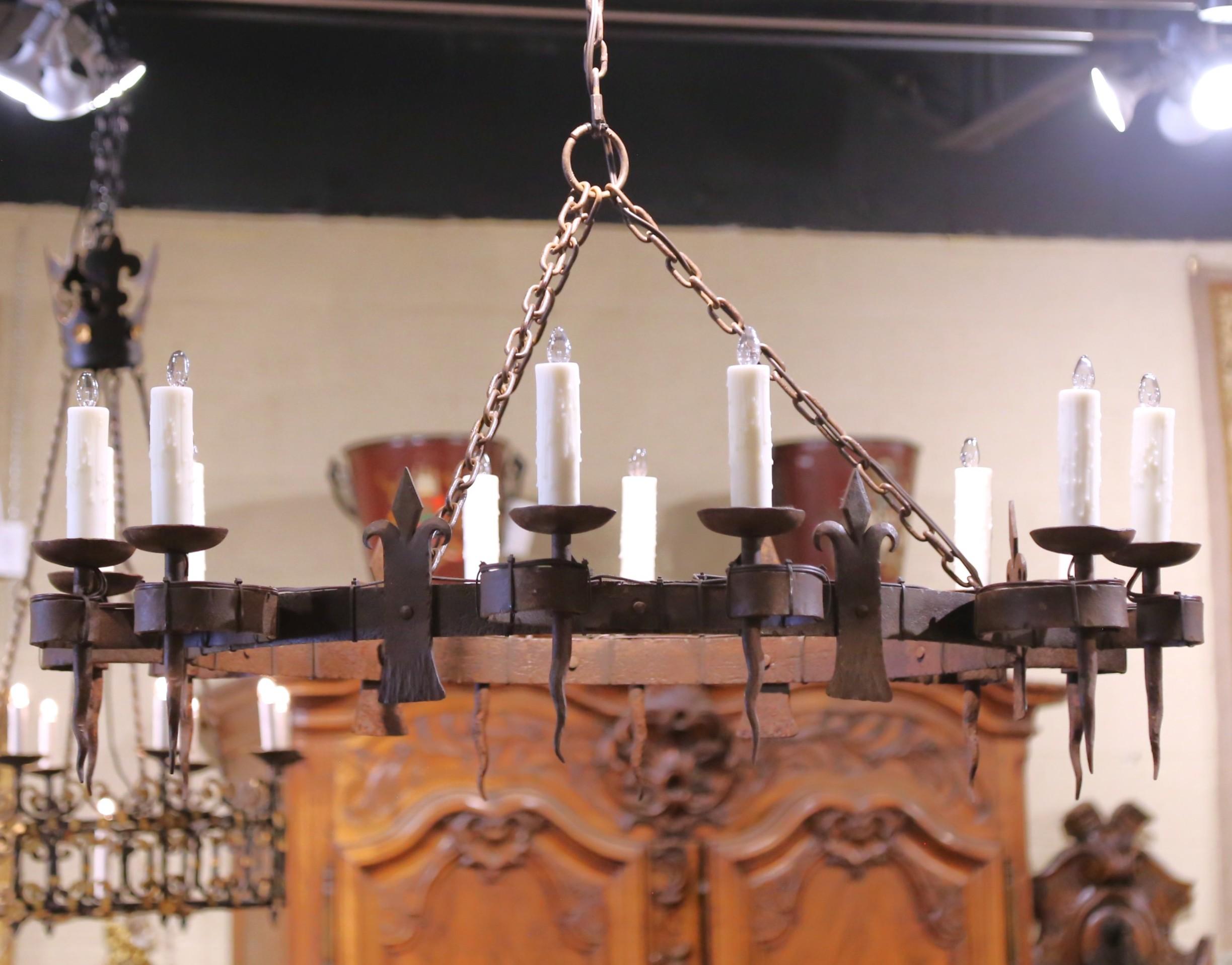 Place this large antique light fixture over a dining table, or in a den. Forged in Normandy France circa 1880, and almost four feet in diameter, the large chandelier built of solid wrought iron, features a circular crown decorated with multiple