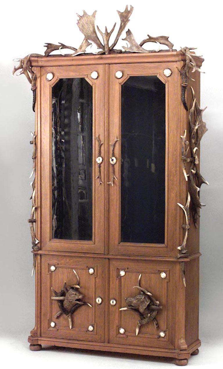 Rustic Continental German (19th Century) oak and horn trimmed 4 door bookcase cabinet with small interior drawers and antler pediment with carved dogs at base
