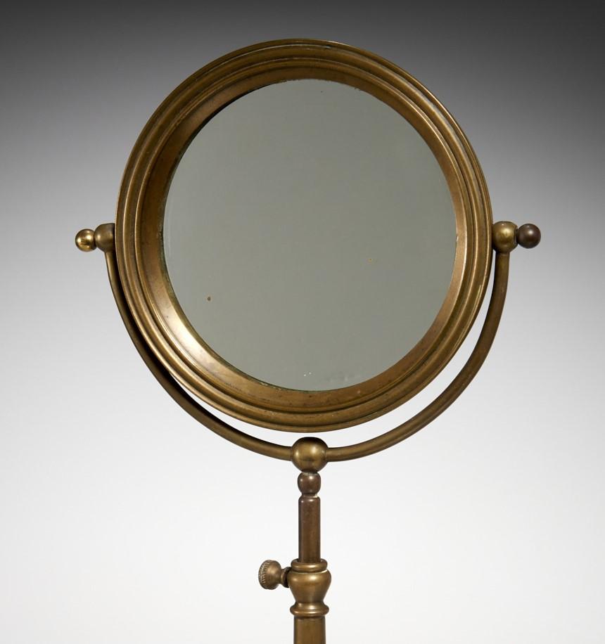 19th c., Gilded Age, a heavily cast bronze tabletop shaving/cosmetic mirror, unmarked. The height of the mirror can be easily adjusted upward or downward. The porthole style mirror can be pivoted to adjust for optimal viewing.

Dimensions:
23.5