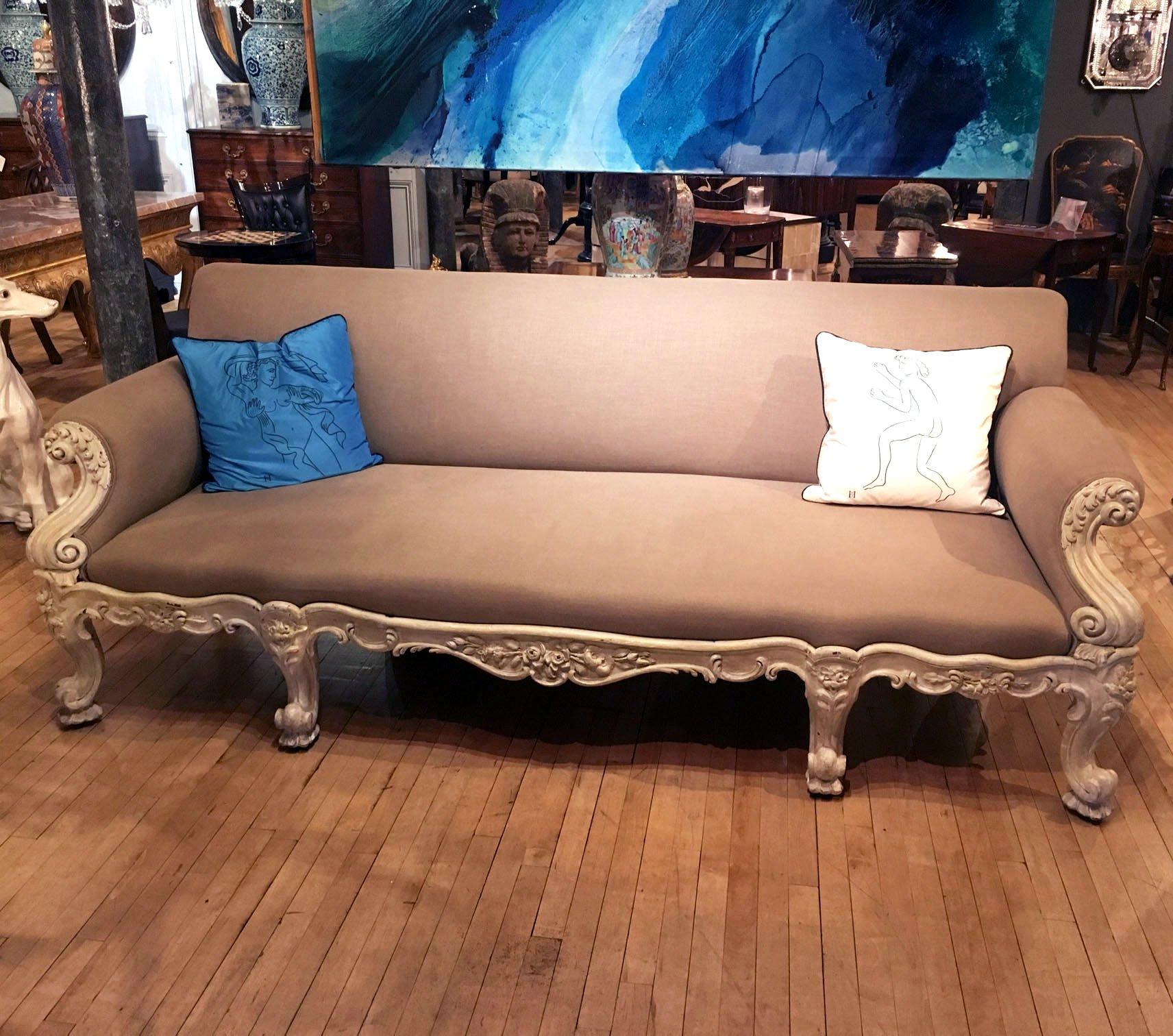 This superb and highly detailed mid-19th century. Gillows carved hardwood sofa features a lovely taupe linen upholstered fabric with a soft cream painted base. The sofa is supported on 8 carved cabriole legs on castors, with substantial rolled arms