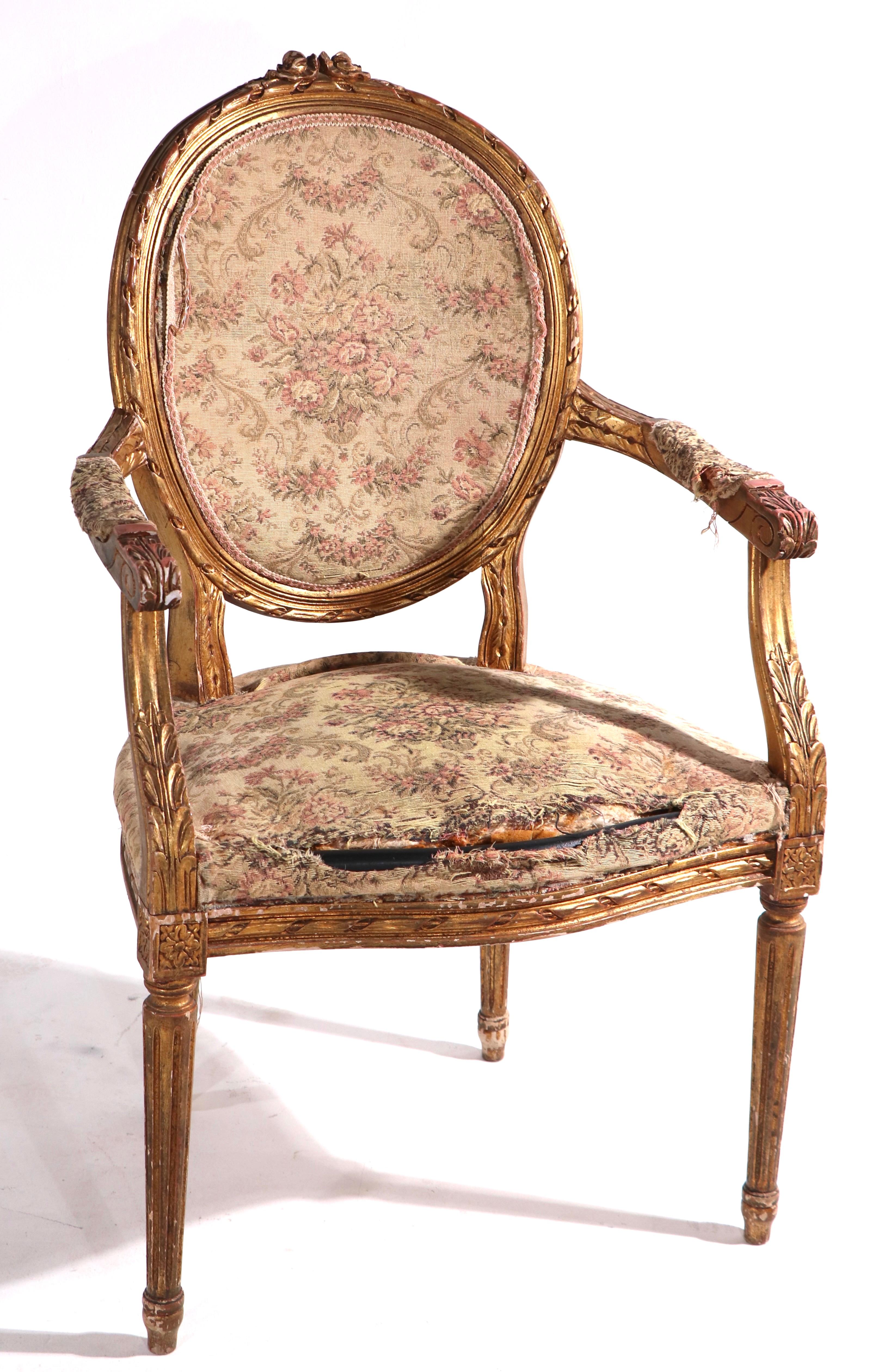 We believe this is a Late 19th, or Early 20th C gilt wood salon chair in as found condition. This elegantly carved wood arm chair is structurally sound and sturdy, it shows wear to the gilt finish, and will need to be reupholstered. Louis XVI style,