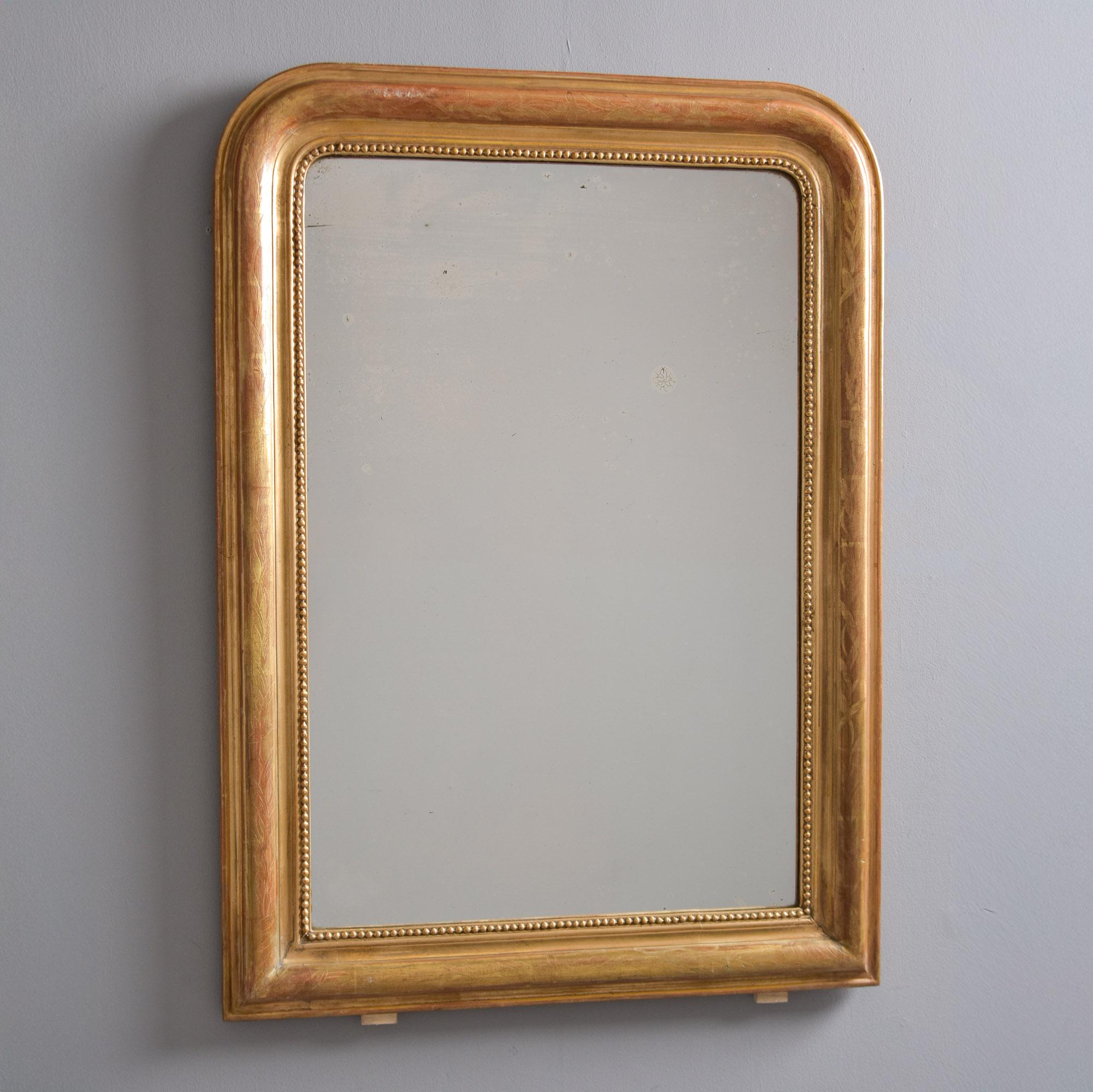 Found in France, this Louis Philippe mirror dates from the 1870s-1880s. Original giltwood frame, newer glass mirror. Frame is just over 40” tall and features a beaded inner edge and top surface of frame is subtly etched with a vine/leaf border.