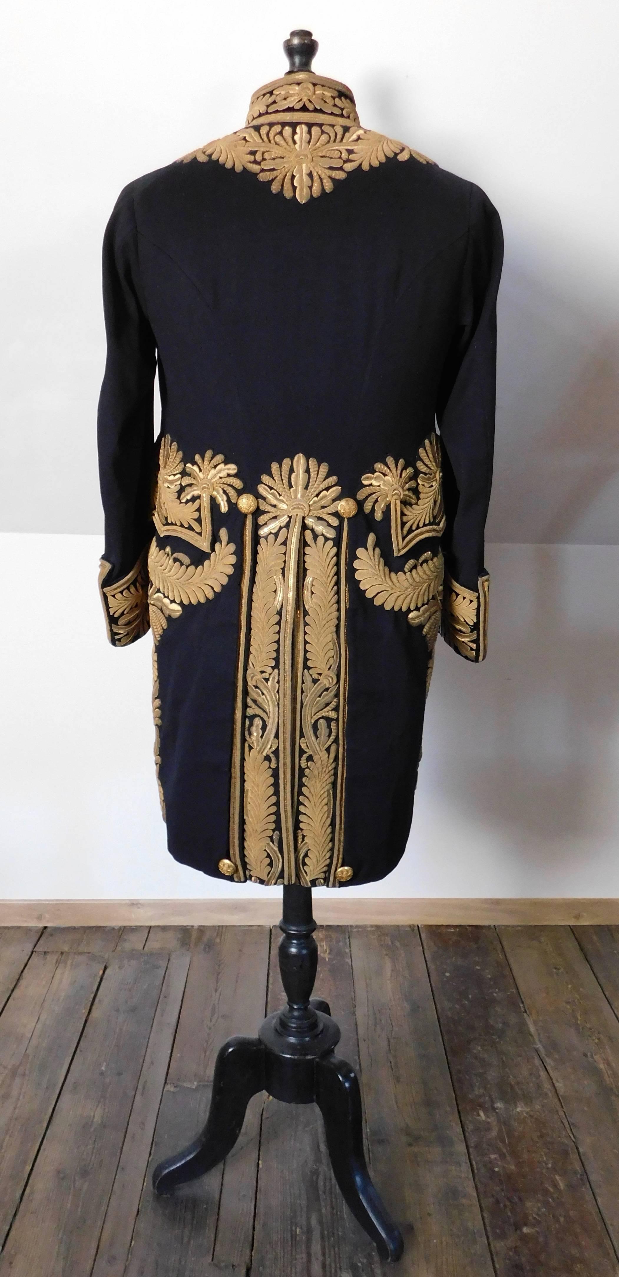 19th century fine black wool tailcoat decorated overall with heavy raised work gold bullion foliage embroidery. Original gilt brass buttons bearing the Royal Coat of Arms (with lion and unicorn) and hidden hook closures. The interior is lined in