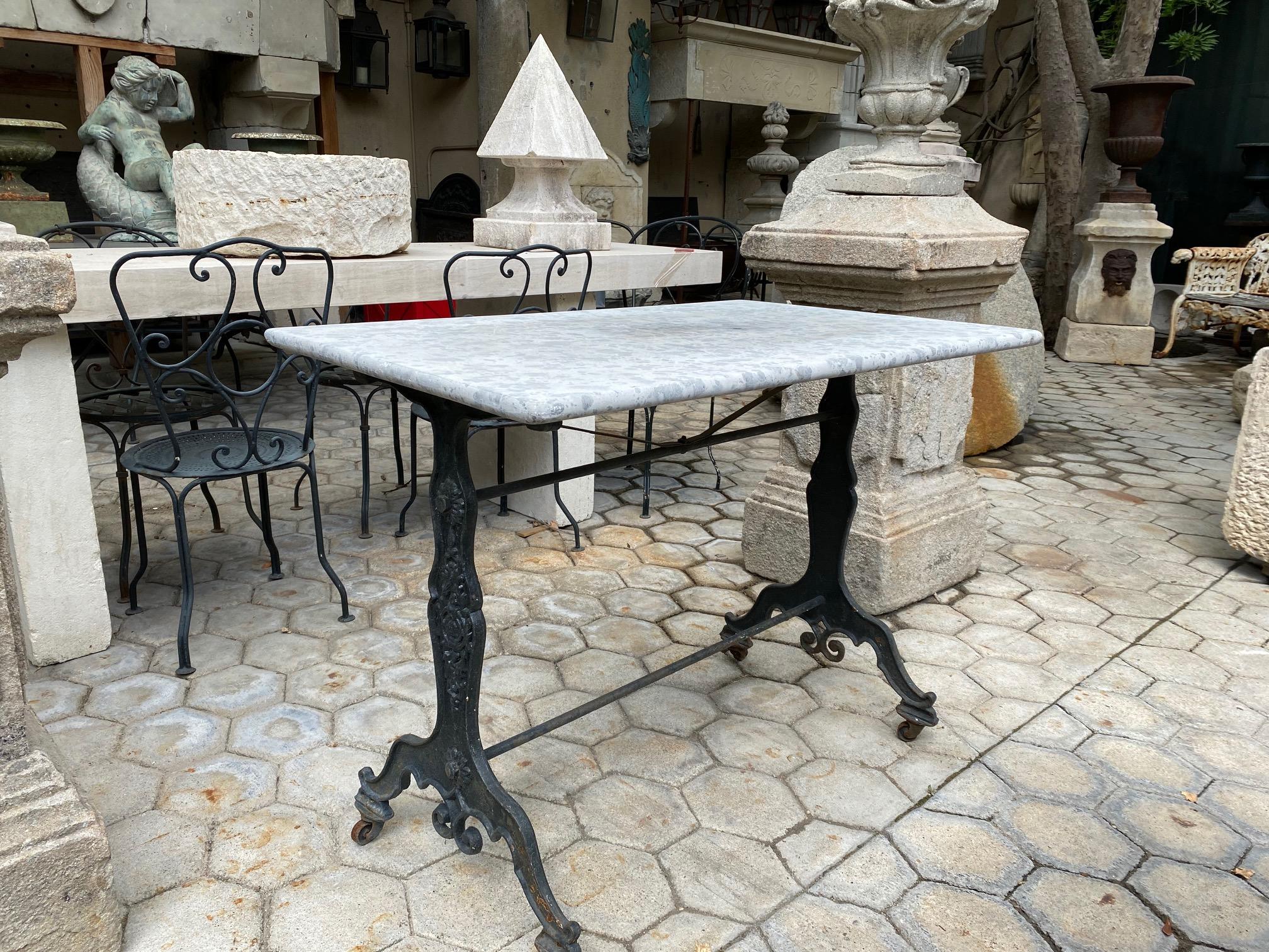 19th century handmade antique garden with original stone marble top and cast iron on casters outdoor indoor table. It will be the perfect touch by an outdoor fireplace as a console, this table has a lot of charm and character. It can work in an old
