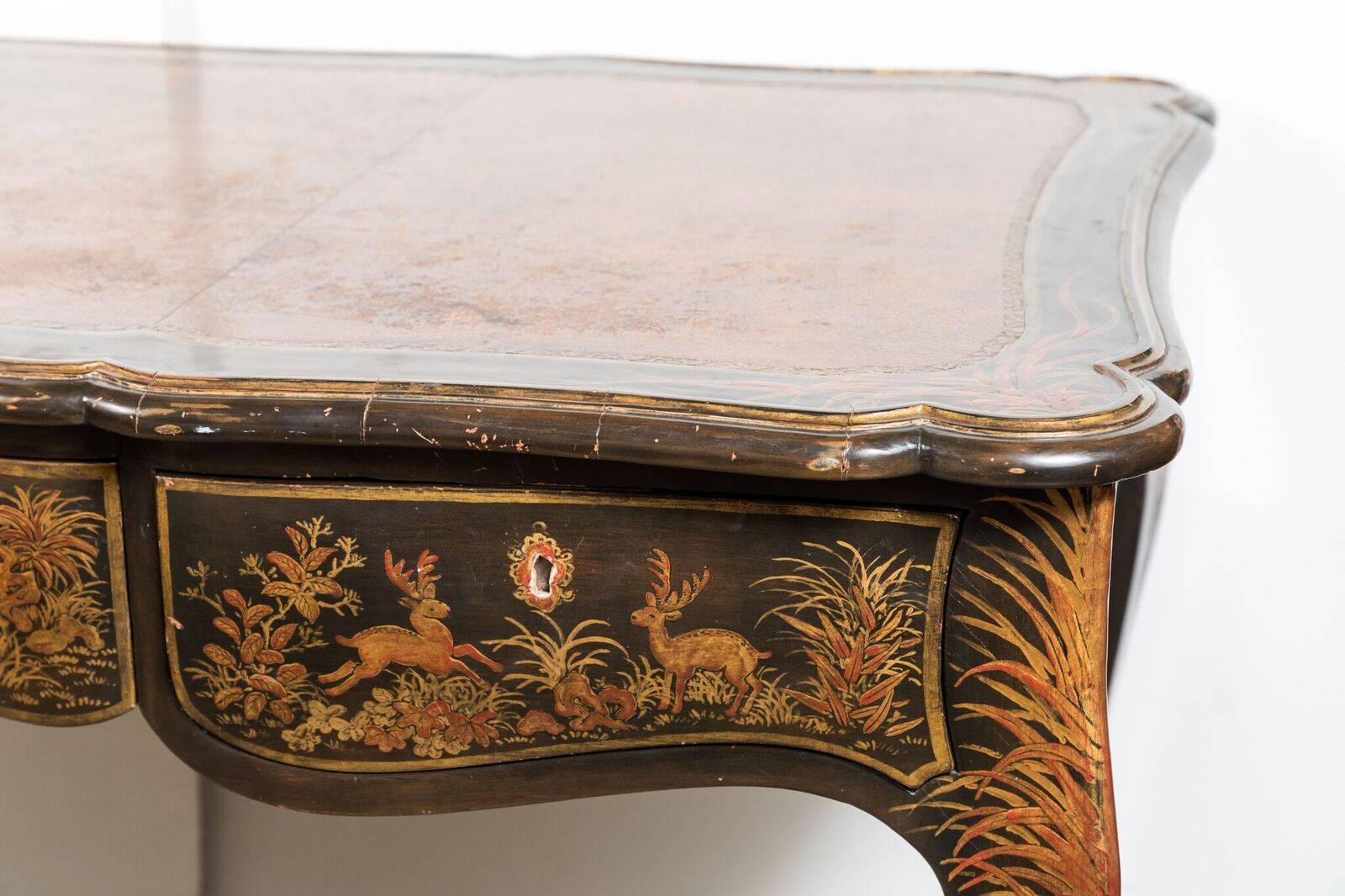 Beautifully hand-painted and lacquered three-drawer desk featuring images of animals and foliage. The embossed leather top surrounded by a lacquered and painted border sitting above a serpentine apron. The whole on cabriole legs.