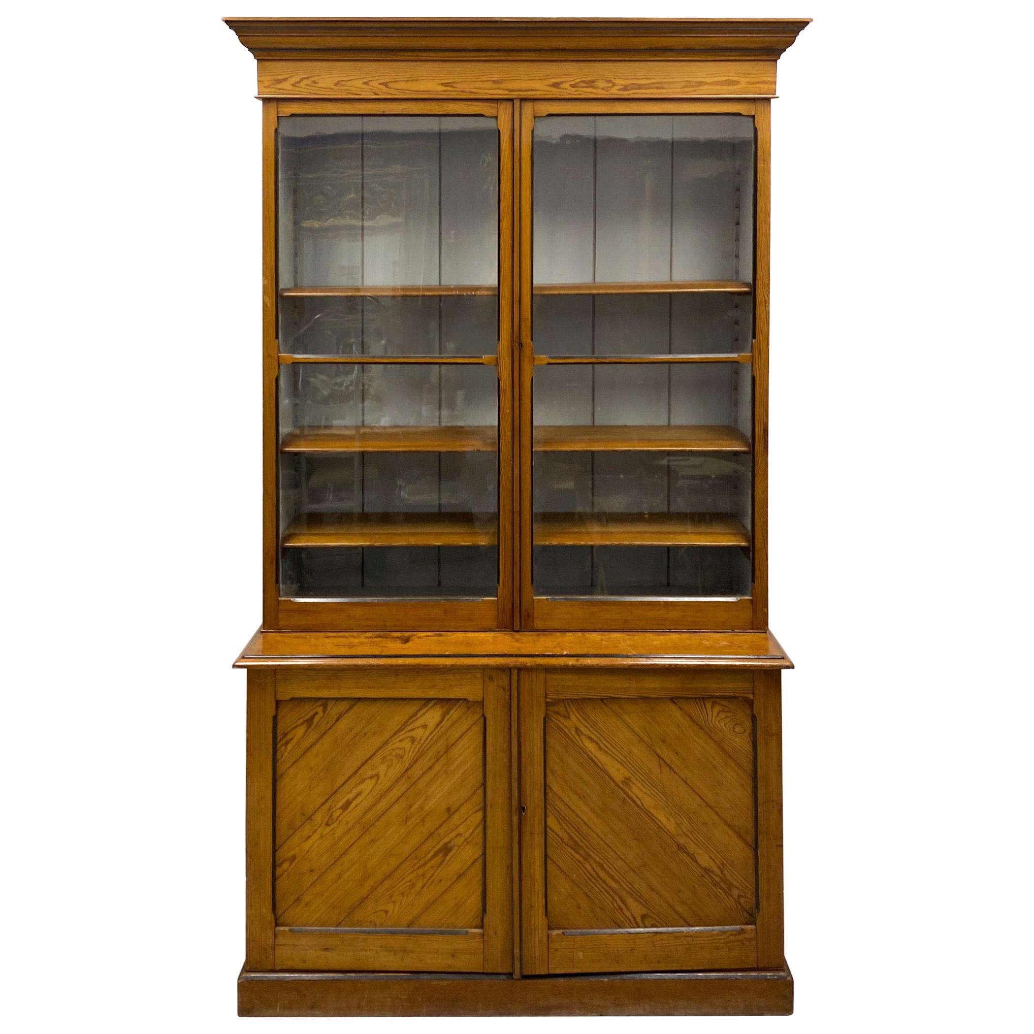 This is a 19th century tall French hard pine cabinet. It does have the original glass as well as tongue in groove construction. The interior is lined with painted beadboard. The top has adjustable shelving, and the base has a single. It does break
